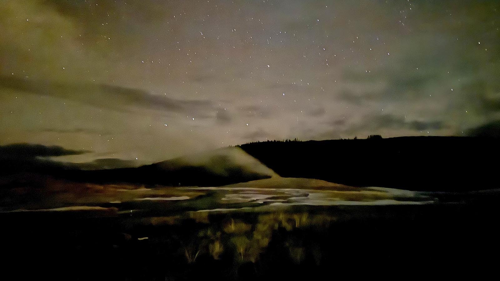 Old Faithful Geyser in Yellowstone National Park percolates under as clear night sky.