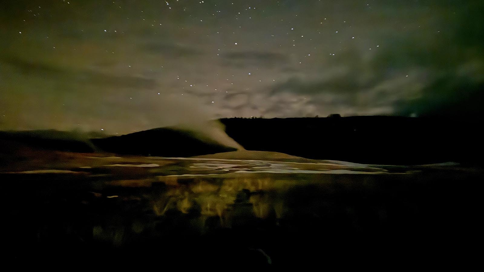 Old Faithful Geyser in Yellowstone National Park percolates under as clear night sky.