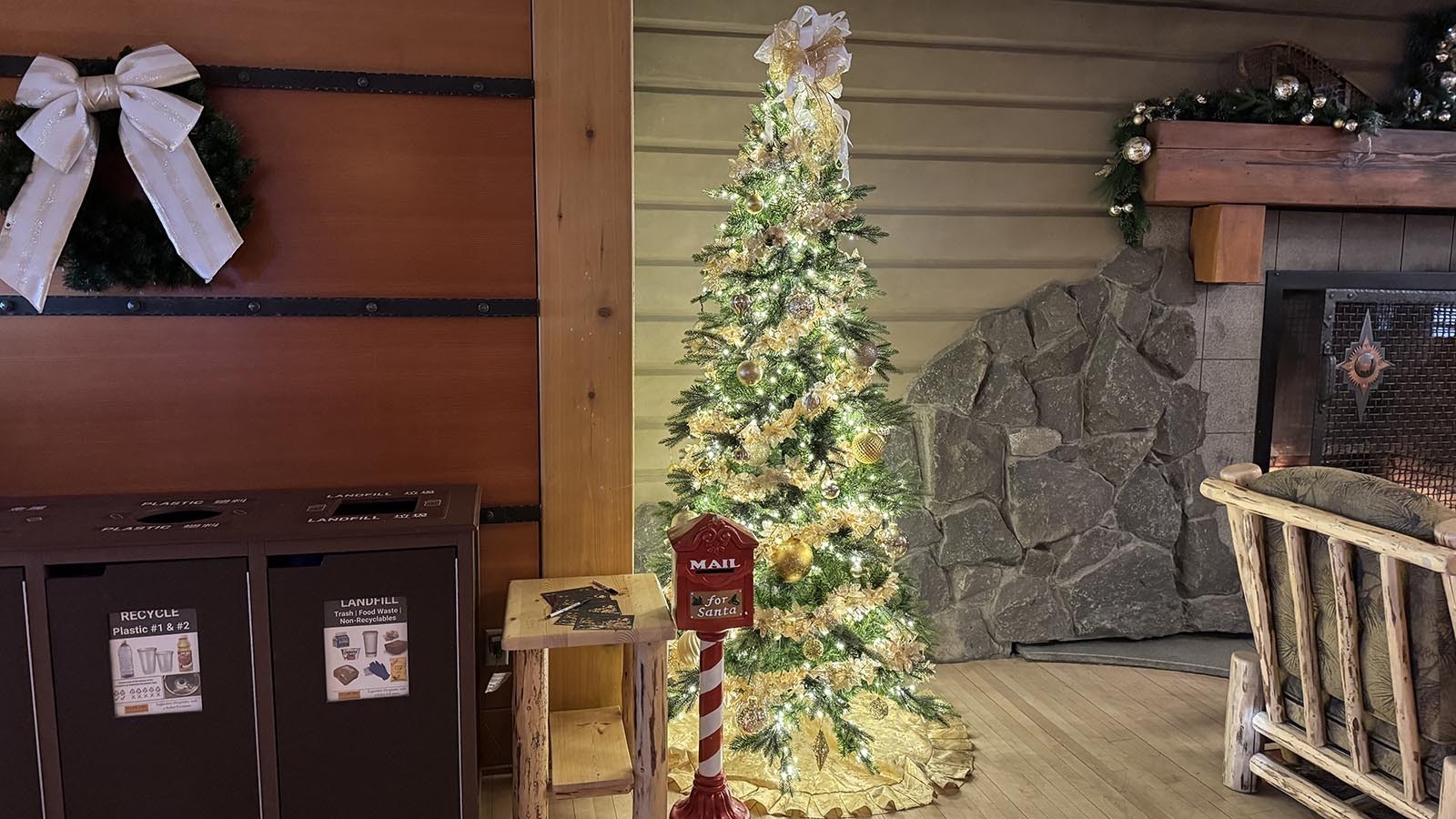 A mailbox for North Pole postcard stands next to a lighted tree and the fireplace in the lobby of the Old Faithful Snow Lodge.