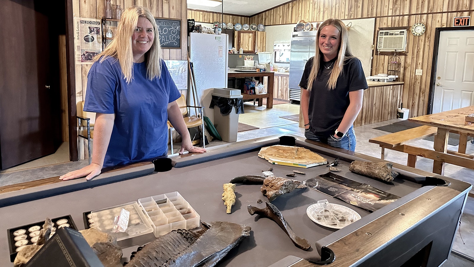 Kris and Kaden Stauffer stand in the Paleo Park Lodge on the Zerbst Ranch. The table contains replicas of various dinosaur fossils that were or could be found on their 7,000-acre property, which has already produced amazing dinosaur discoveries.