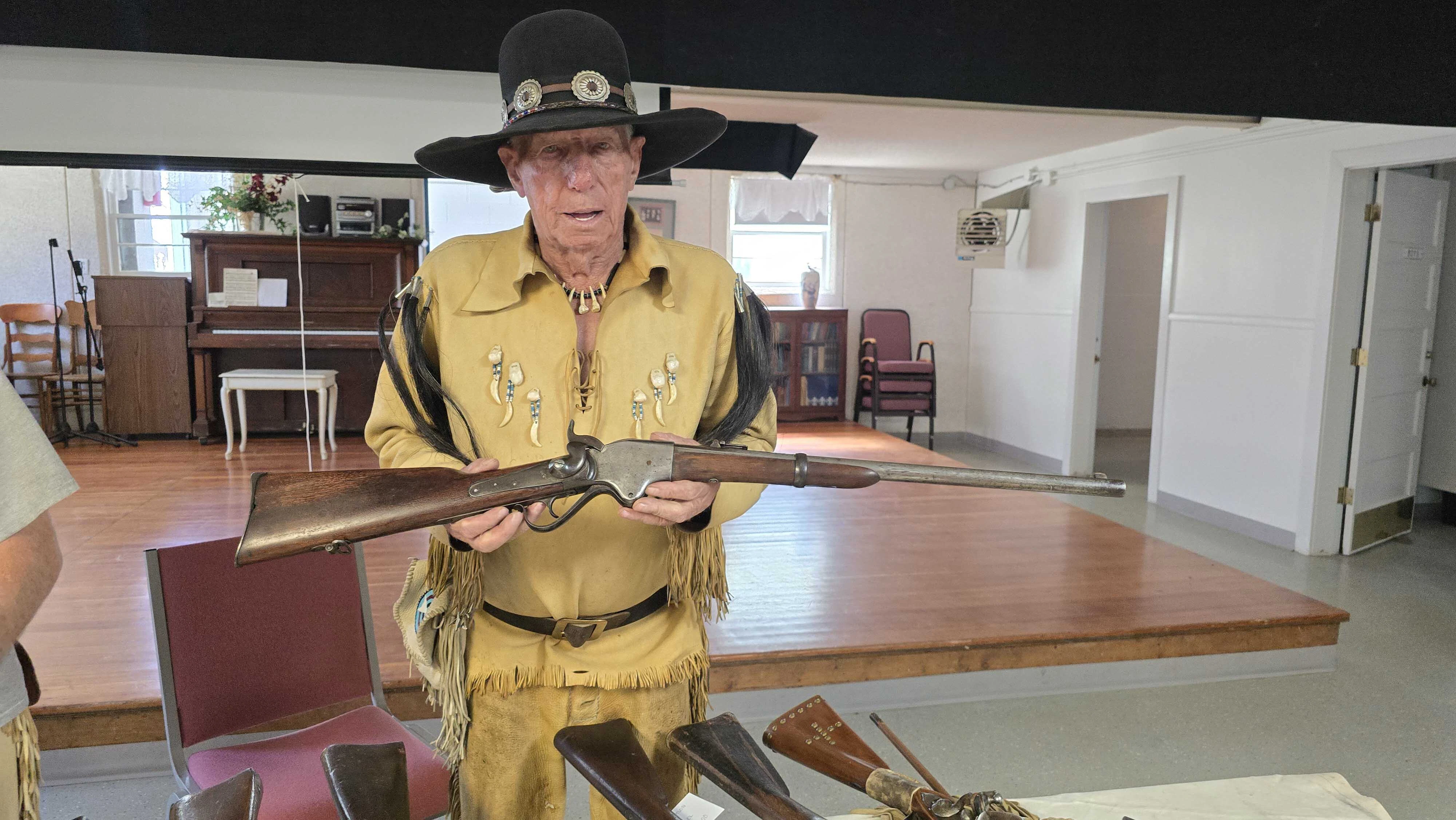 Robert Golden holds up a Spencer repeating carbine during activities for to celebrate restoration work for the Jim Baker cabin. That's the type of gun that blew up in Jim Baker's face during a demonstration. Baker survived the incident, but the explosion blew off his jaw. He grew a beard to hide that and usually kept his face turned a particular way for photos as a result.