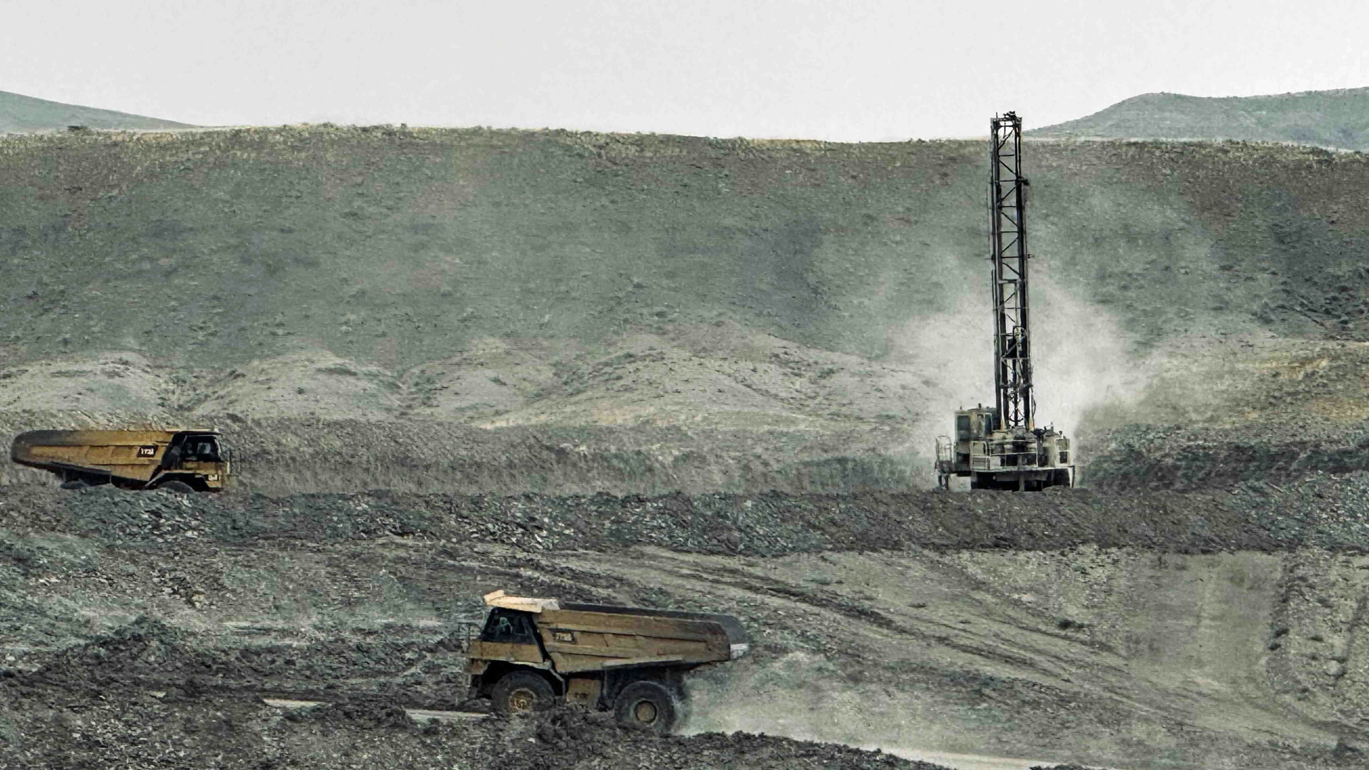 Above, a haul truck is removing overburden off one of the layers of bentonite in the Bighorn Basin. Behind the truck, a drill rig is drilling holes for the next blast to remove rock.