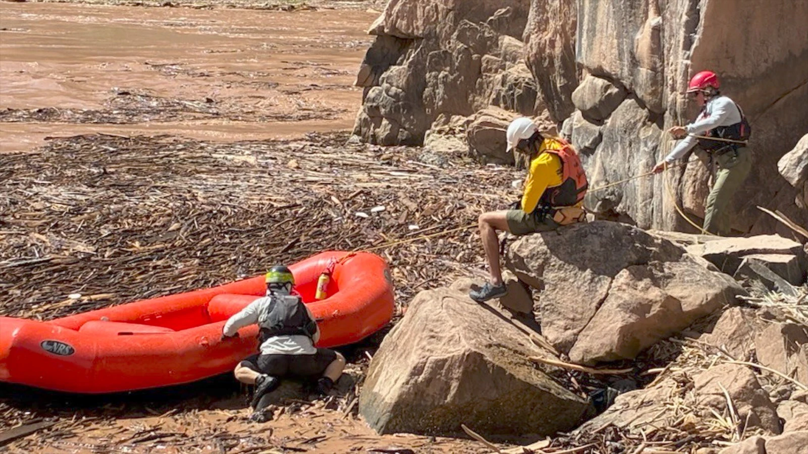 Three search and rescue personnel secure a raft to the shoreline on the Colorado River in the Grand Canyon.