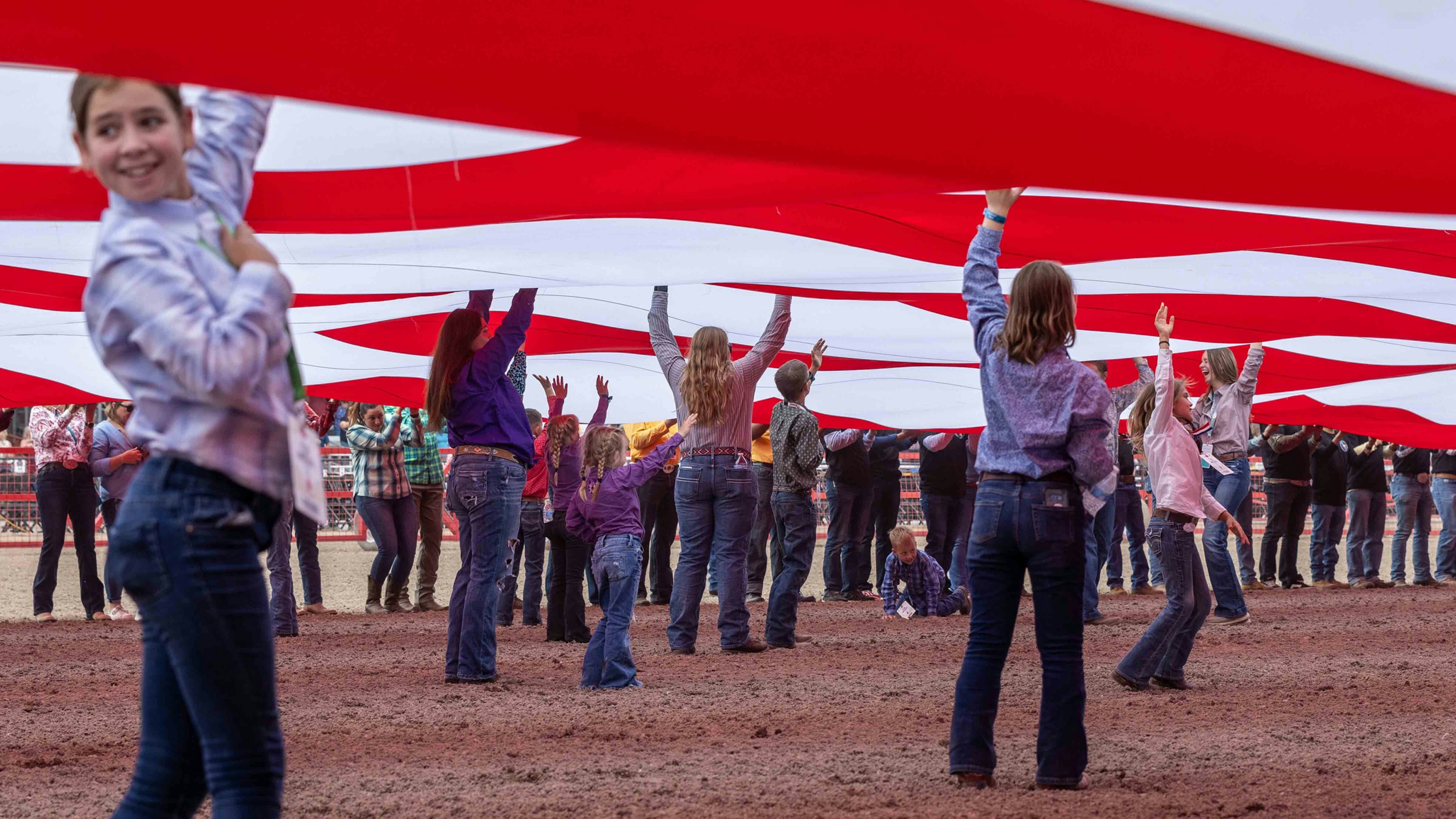 Volunteers hold up the arena-sized flag during Military Monday at Cheyenne Frontier Days on July 22, 2024