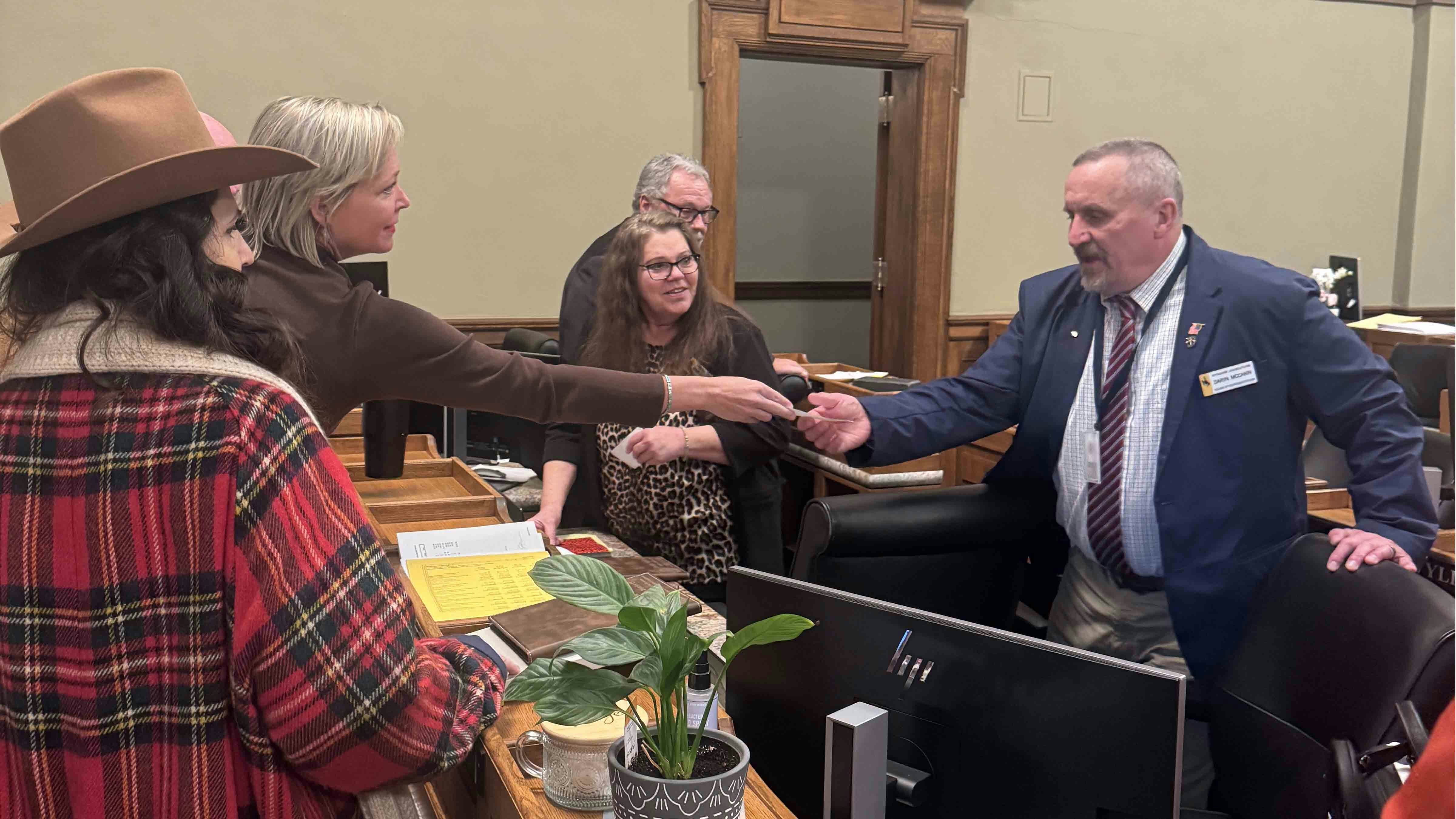 Rebecca Bextel (left) hands a check to Rep. Darin McCann, R-Rock Springs, on Monday, Feb. 9, 2026