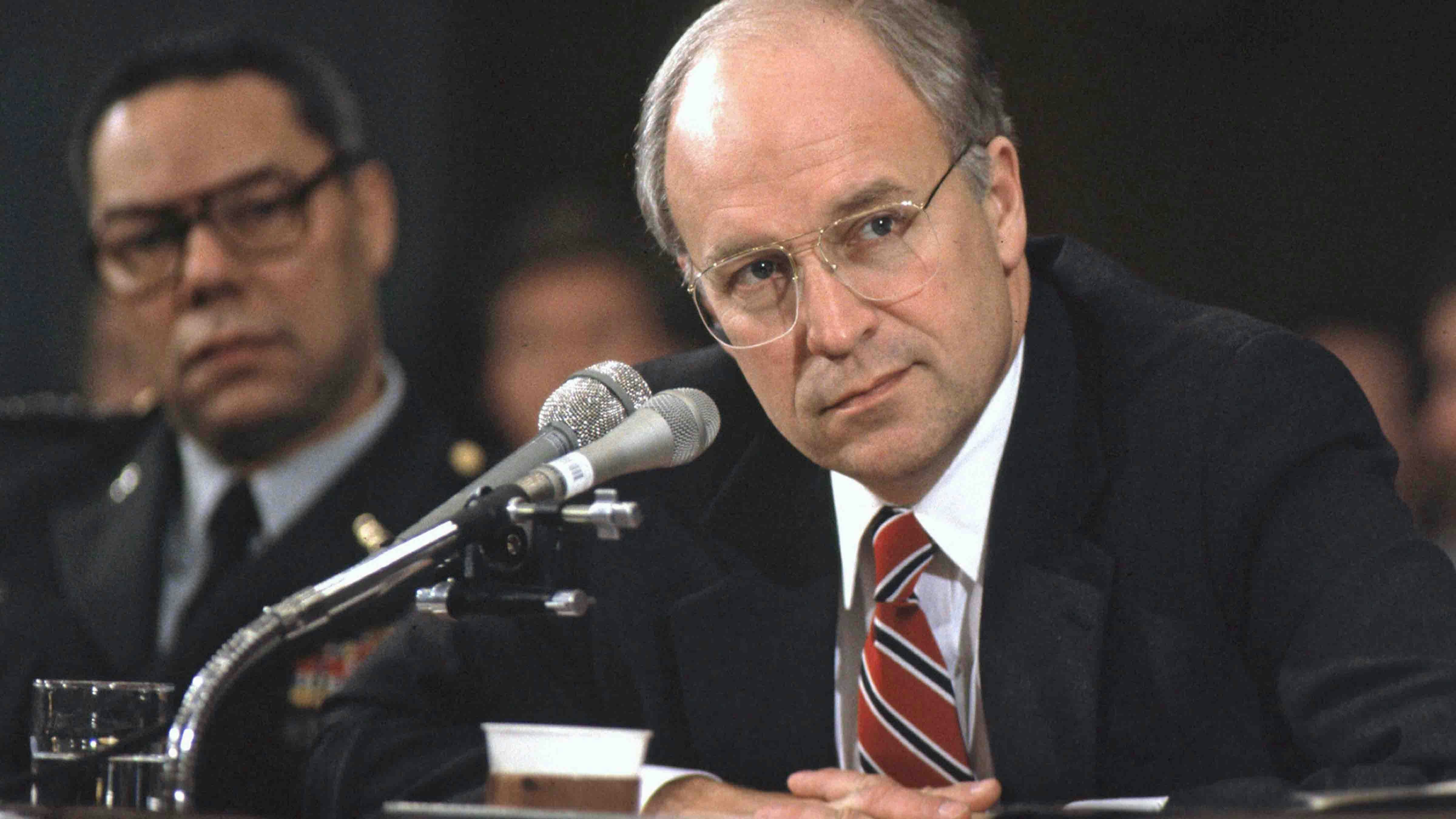 Former United States Secretary of Defense Richard (Dick) Cheney, who is rumored to be Republican Gov. George W. Bush's selection for the Vice Presidential nomination, testifies before the U.S. Senate Armed Services Committee in Washington, DC on the Persian Gulf crisis on 30 November, 1990. General Colin Powell, Chairman of the Joint Chiefs of Staff, looks on at left.