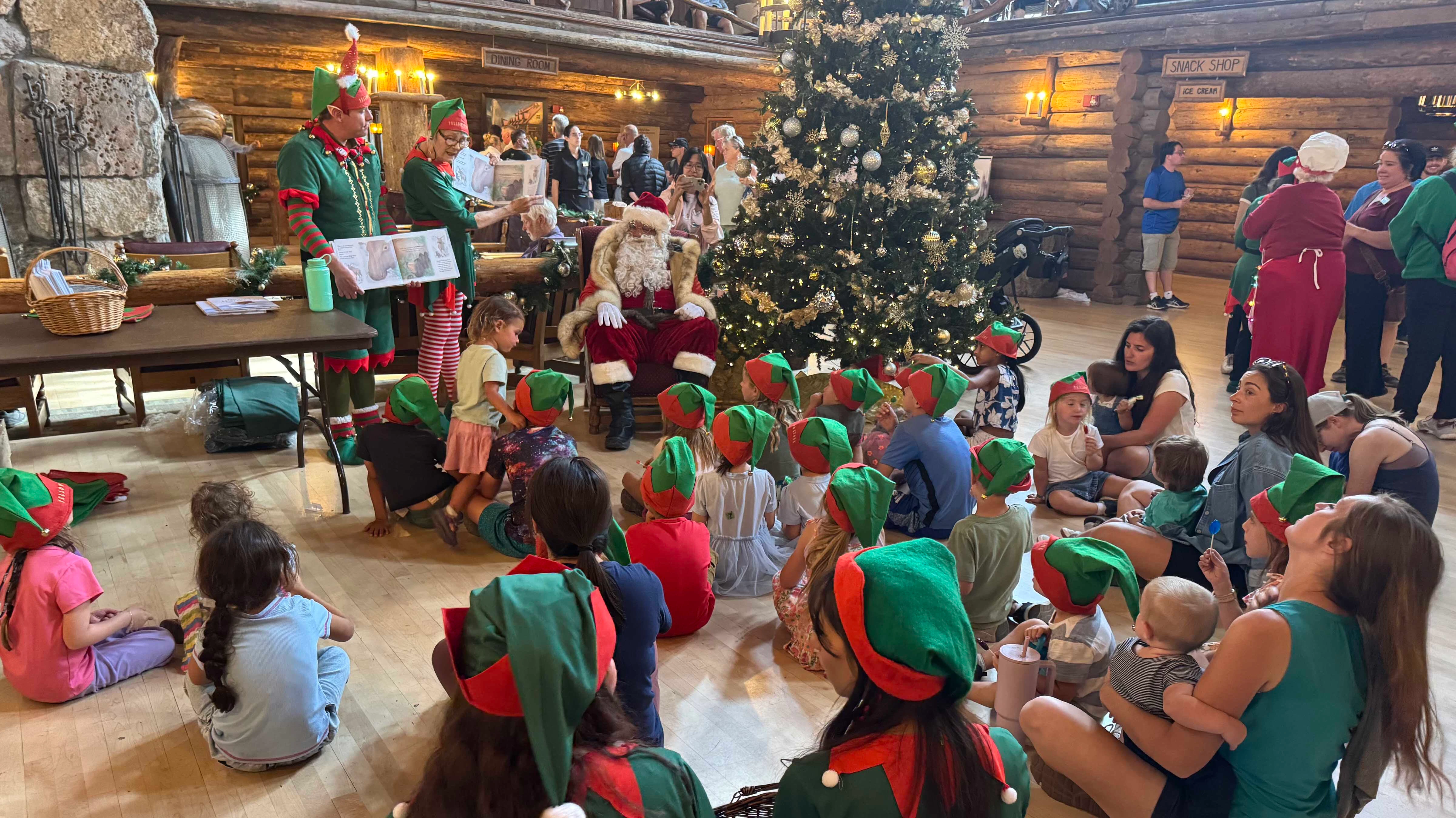 Santa Claus and his elves entertain tourists in the towering lobby of the Old Faithful Inn in an August tradition.