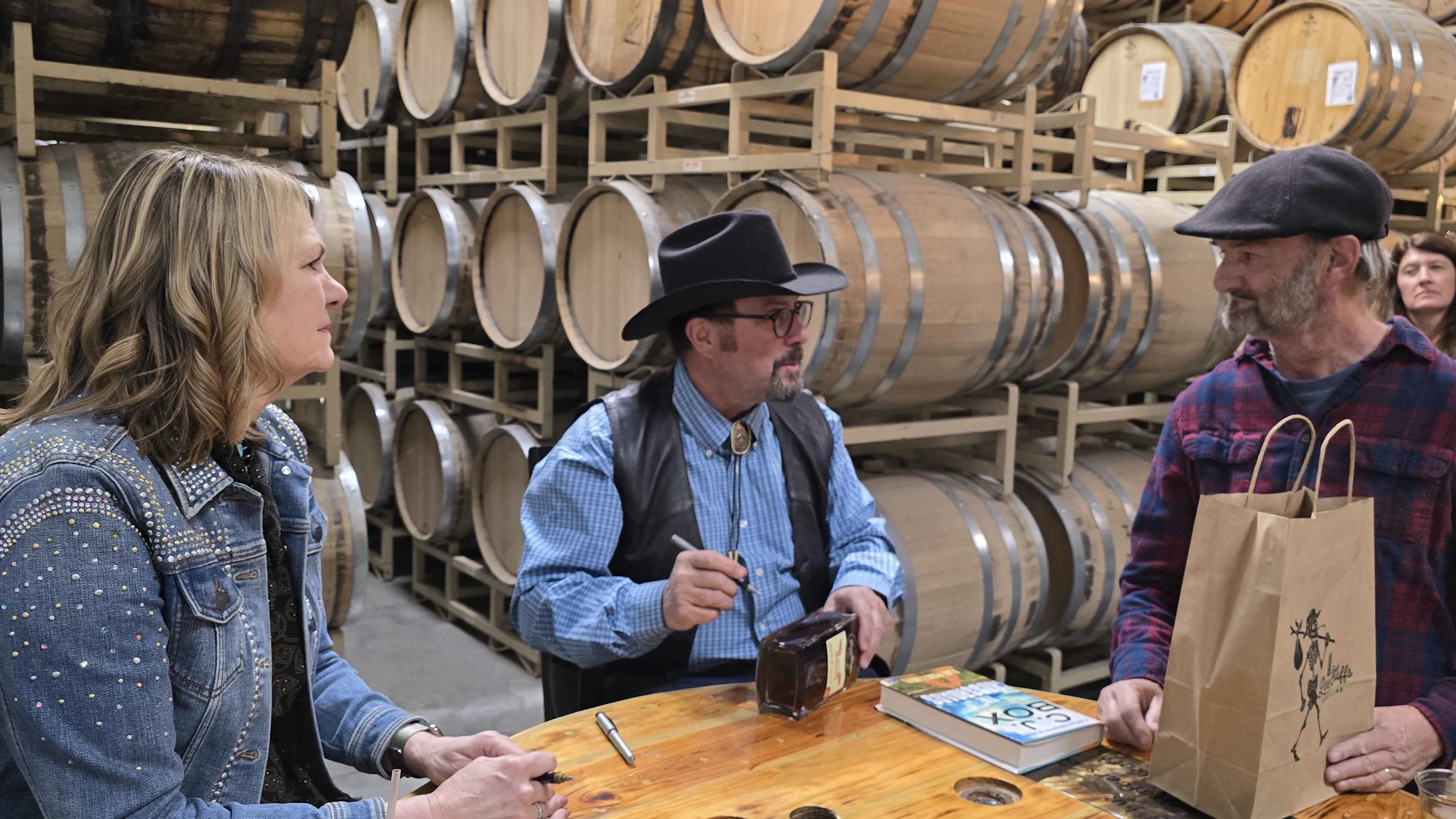 Tony Dix, right, gets a book and a bottle of Romanowski Rye signed by Wyoming First Lady Jenny Gordon, left, and New York Times bestselling author C.J. Box during an event in Pine Bluffs that attracted hundreds of fans and raised $40,000 for charity.