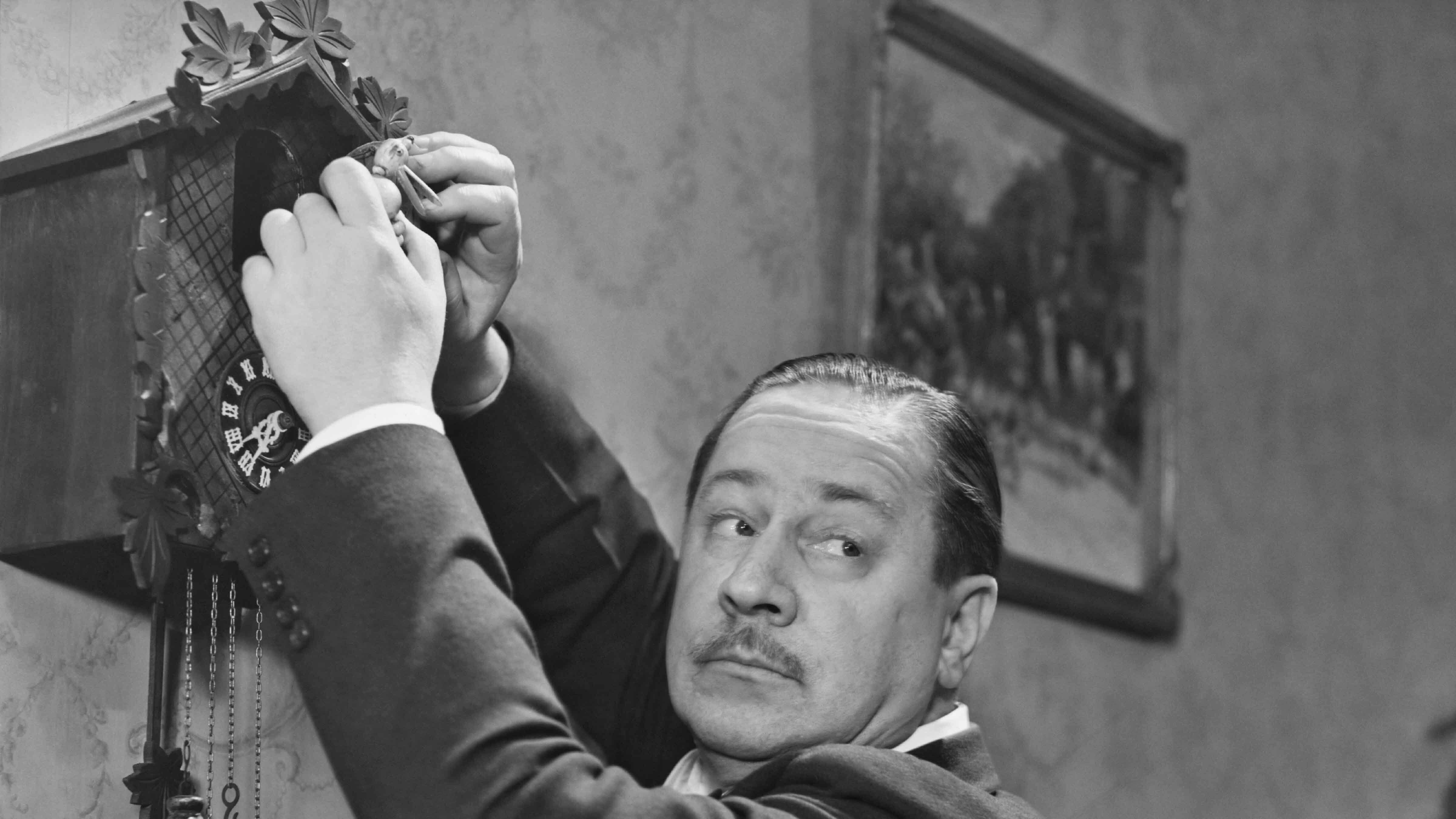 American writer and actor Robert Benchley (1889 - 1945) with a cuckoo clock circa 1940.