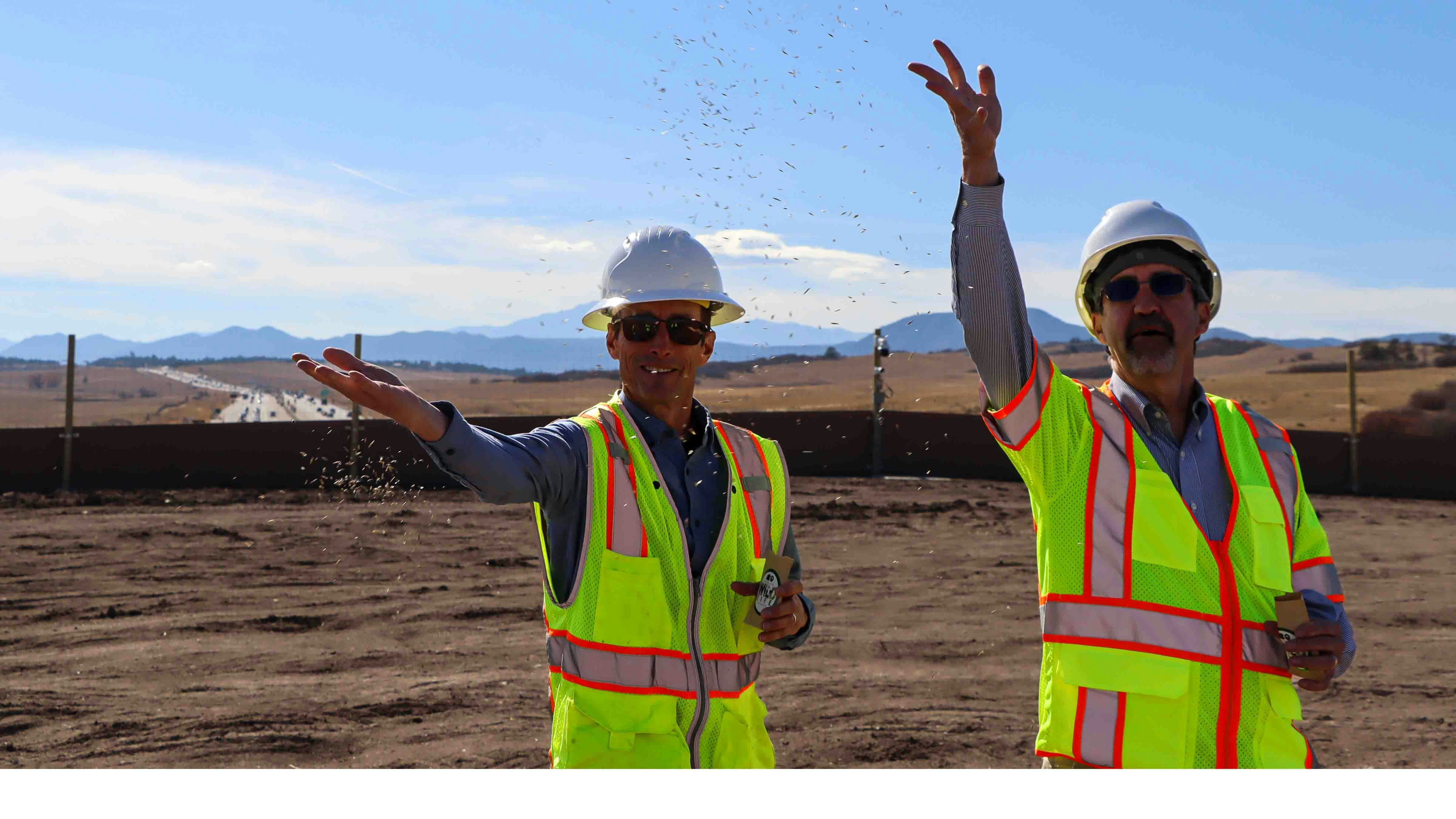 Workers toss seeds to complete the natural look of the Greenland wildlife overpass along Interstate 25 south of Denver.