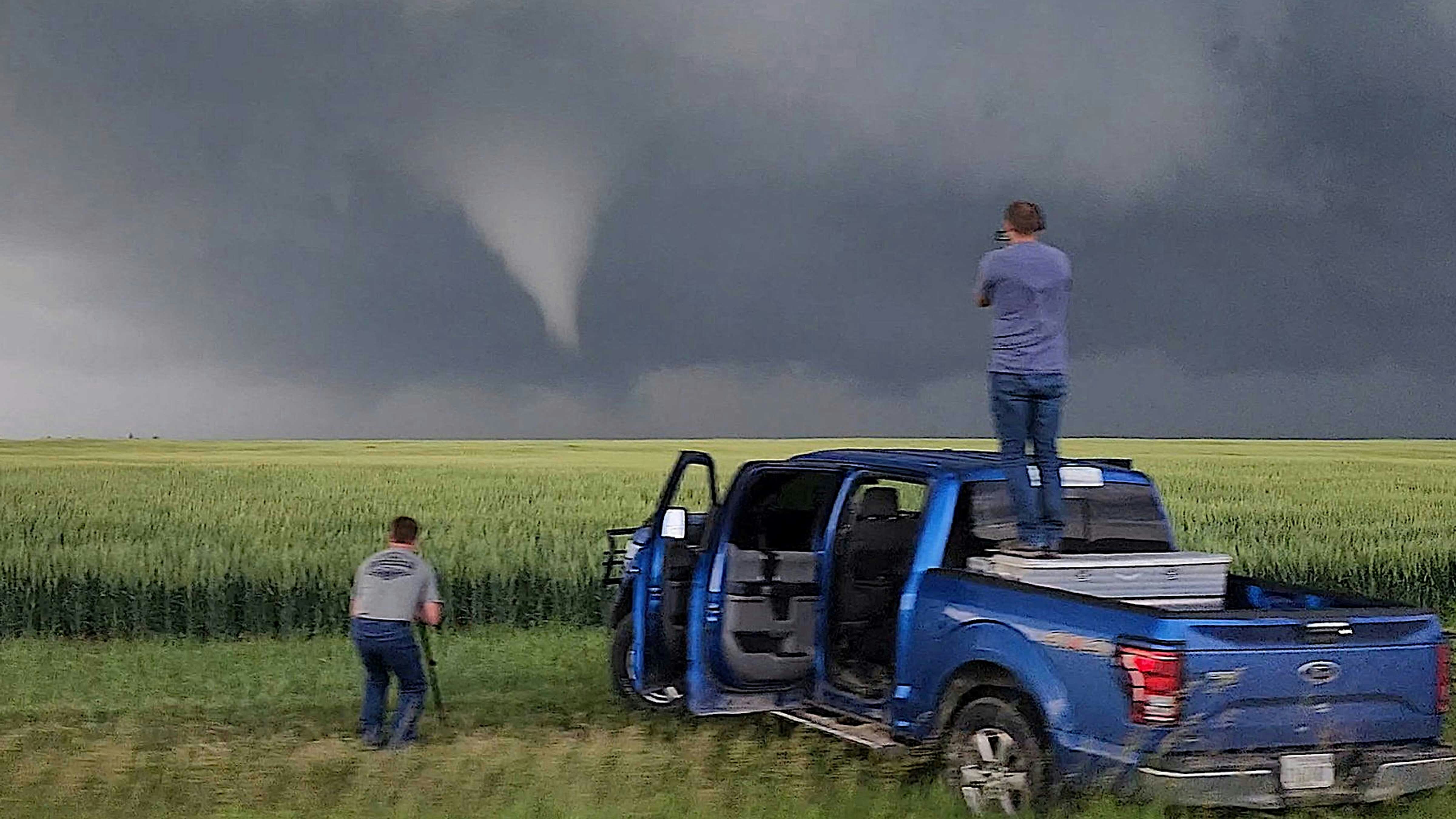 Dan “The Ice Man” Fitts (right) stands on his storm-chasing Ford F-150 spotting a funnel cloud with his chase partner Jerry Doremus.