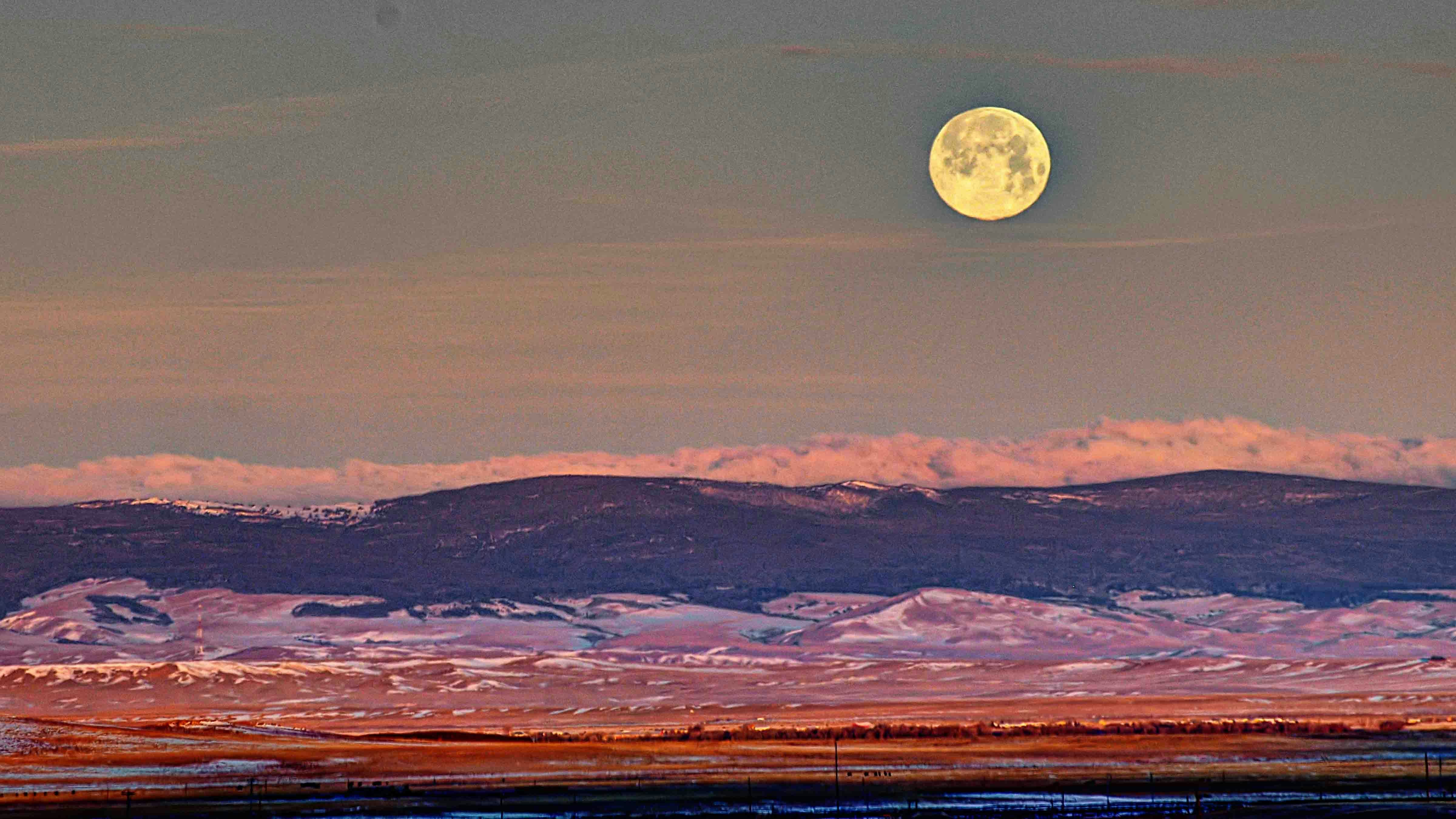Full moon as early sunrise illuminates the Laramie Plains and Medicine Bow Mountains on Jan 26, 2024