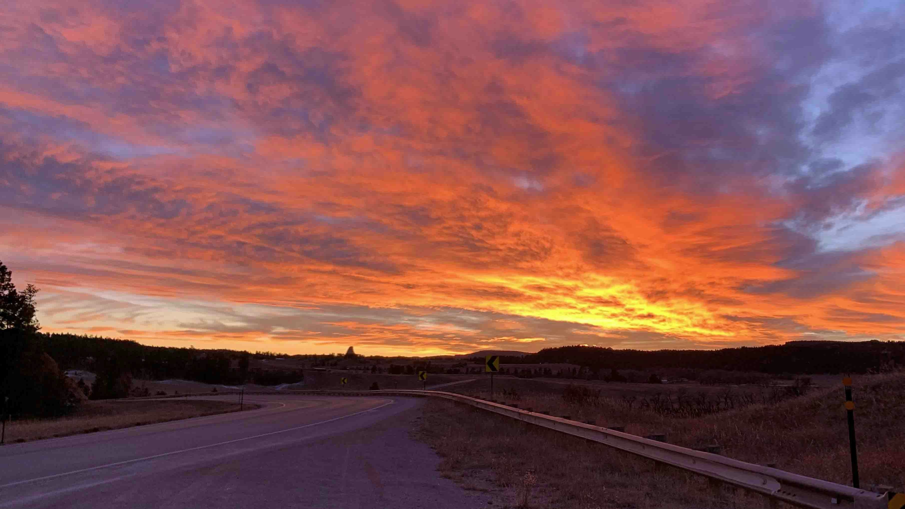 "Sunset in northeast Wyoming. You can see a tiny Devils Tower against a vibrant orange sky."