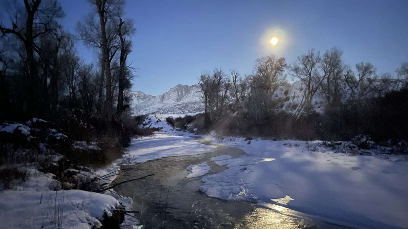 "Bighorn Mountains with a big moon reflecting off Shell Creek."