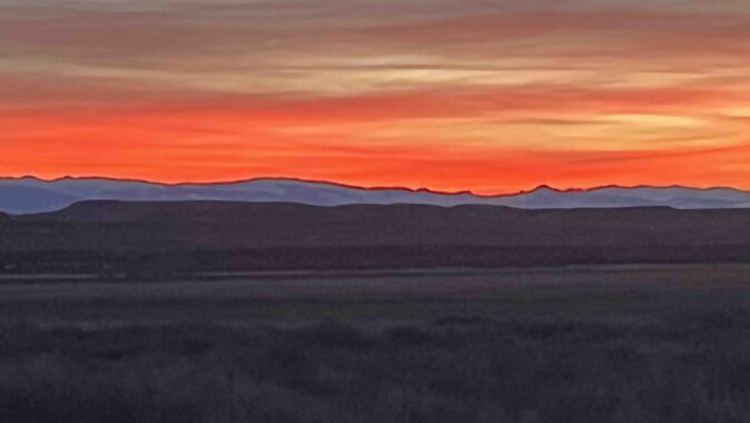 "Sunset over the Wind River Mountains from west of Riverton. The stunning orange highlights the peaks of the skyline."