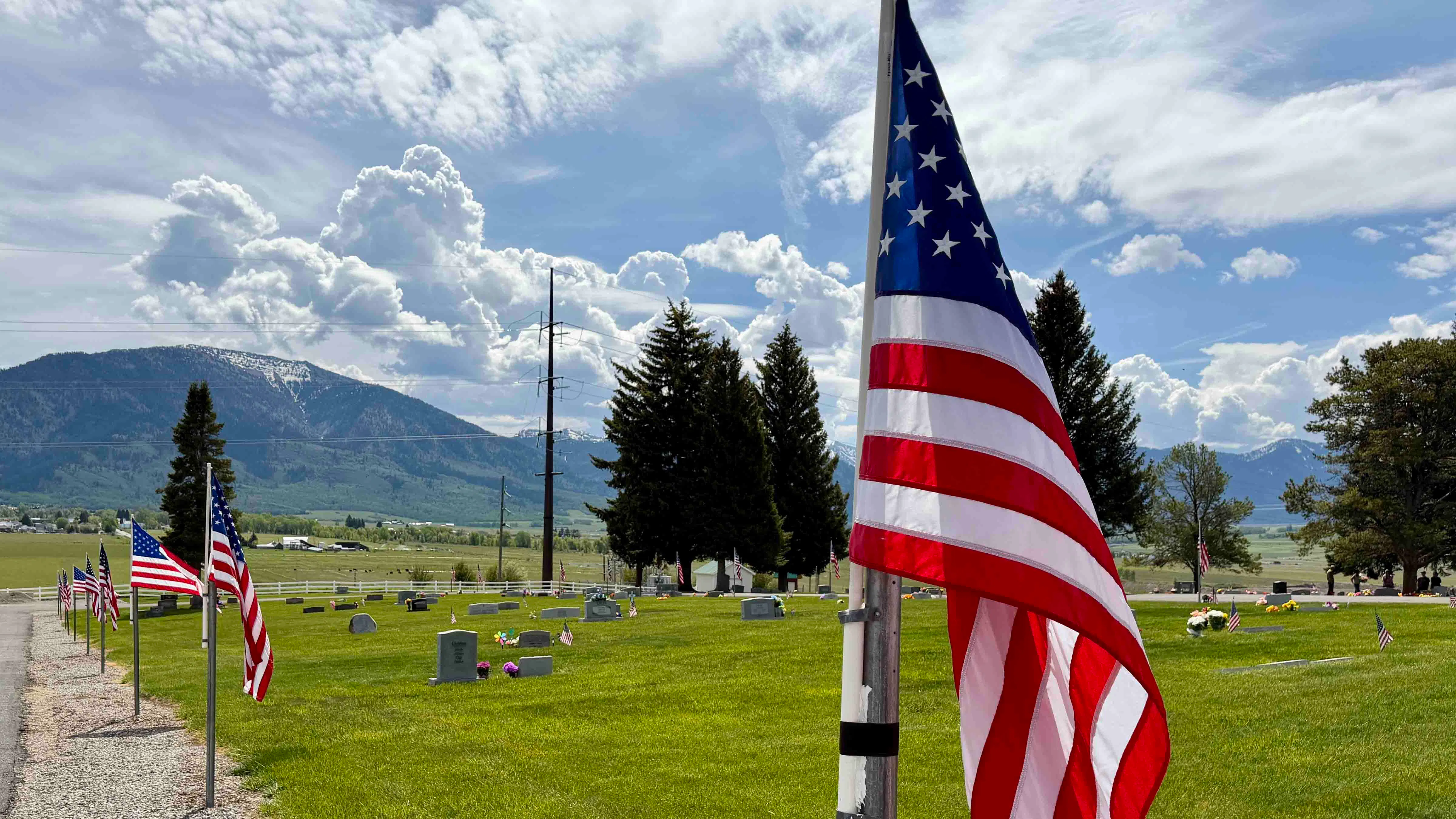 "American flags line the hilltop cemetery in Bedford, Wyoming, with a  beautiful vista of the Salt River Range in the backdrop."