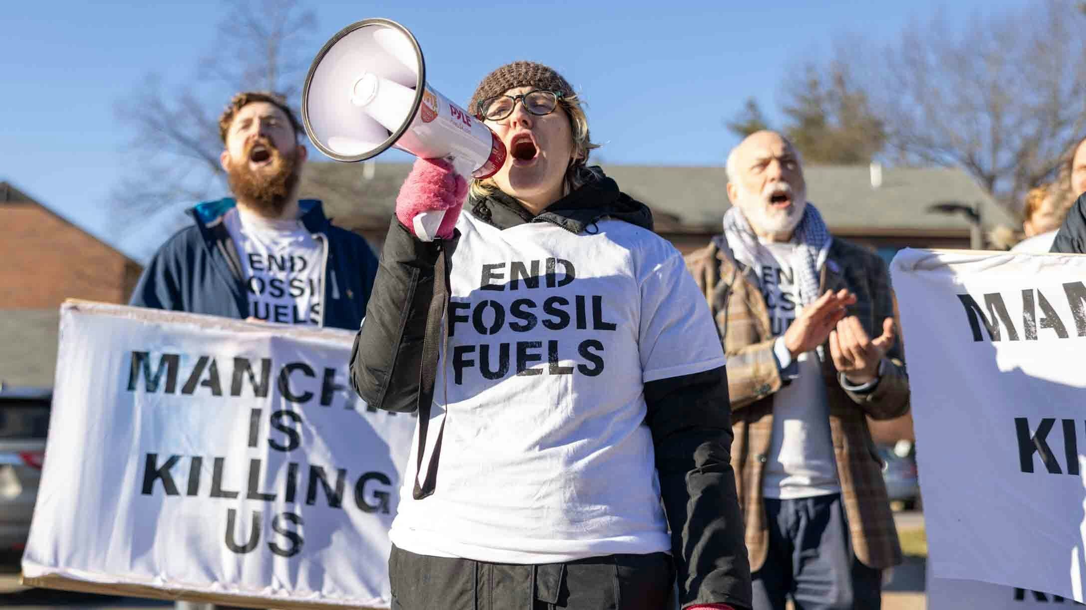 Climate activists hold a protest outside of a "Politics & Eggs" event