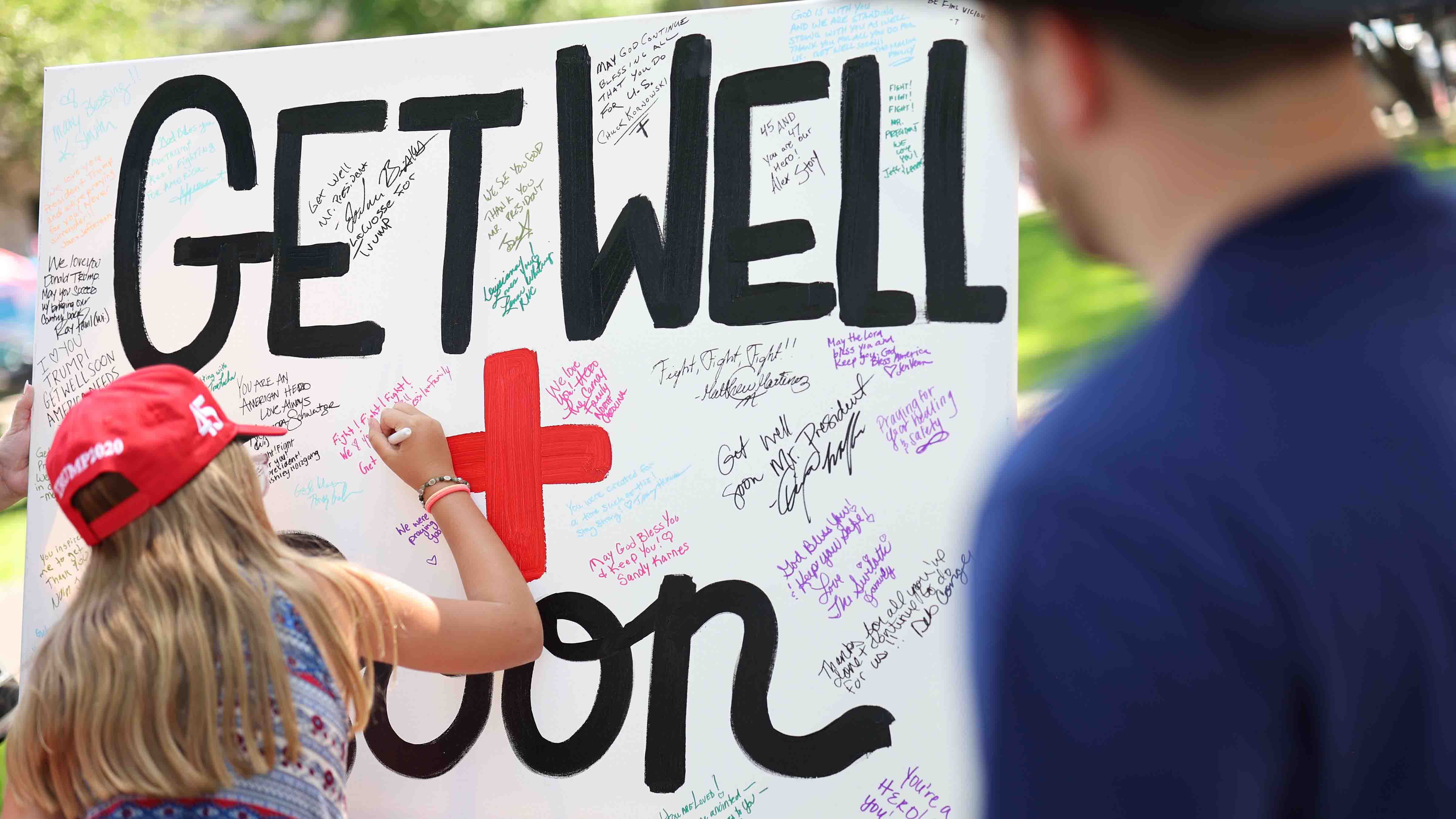 A person writes a message on a Get Well Soon poster board during a vigil for Republican presidential candidate former President Donald Trump at Zeidler Union Square on July 14, 2024 in Milwaukee, Wisconsin.