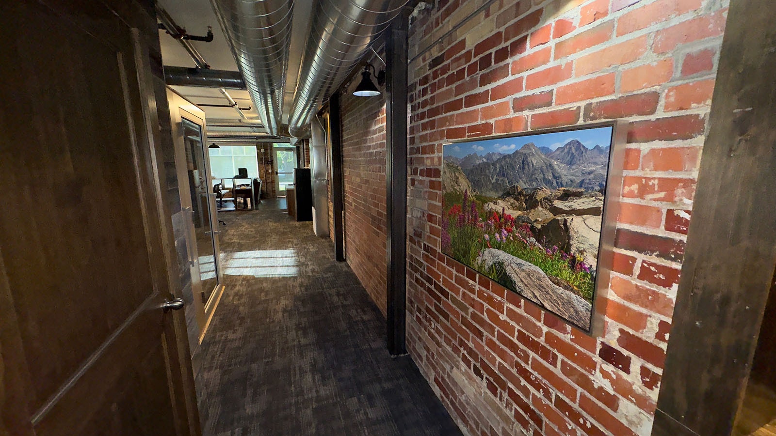 The exposed brick maintains the historic nature of the Irwin Barn. This is a hallway between the main newsroom and the conference room. It's highlighted by a large original print from Wyoming photographer Dave Bell.