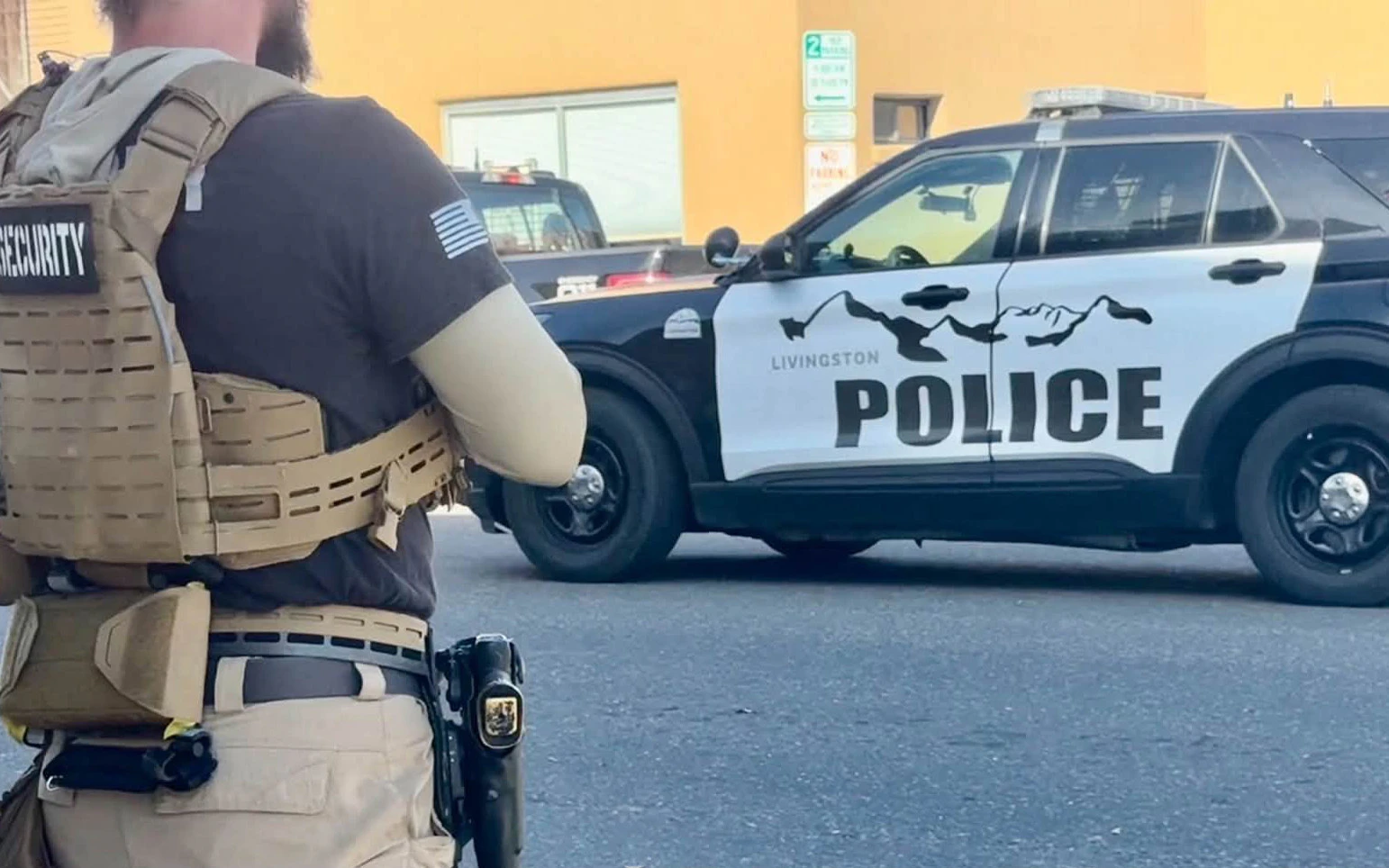 A private security guard stands near a Livingston police car in downtown Livingston during filming of a Daily Wire movie.