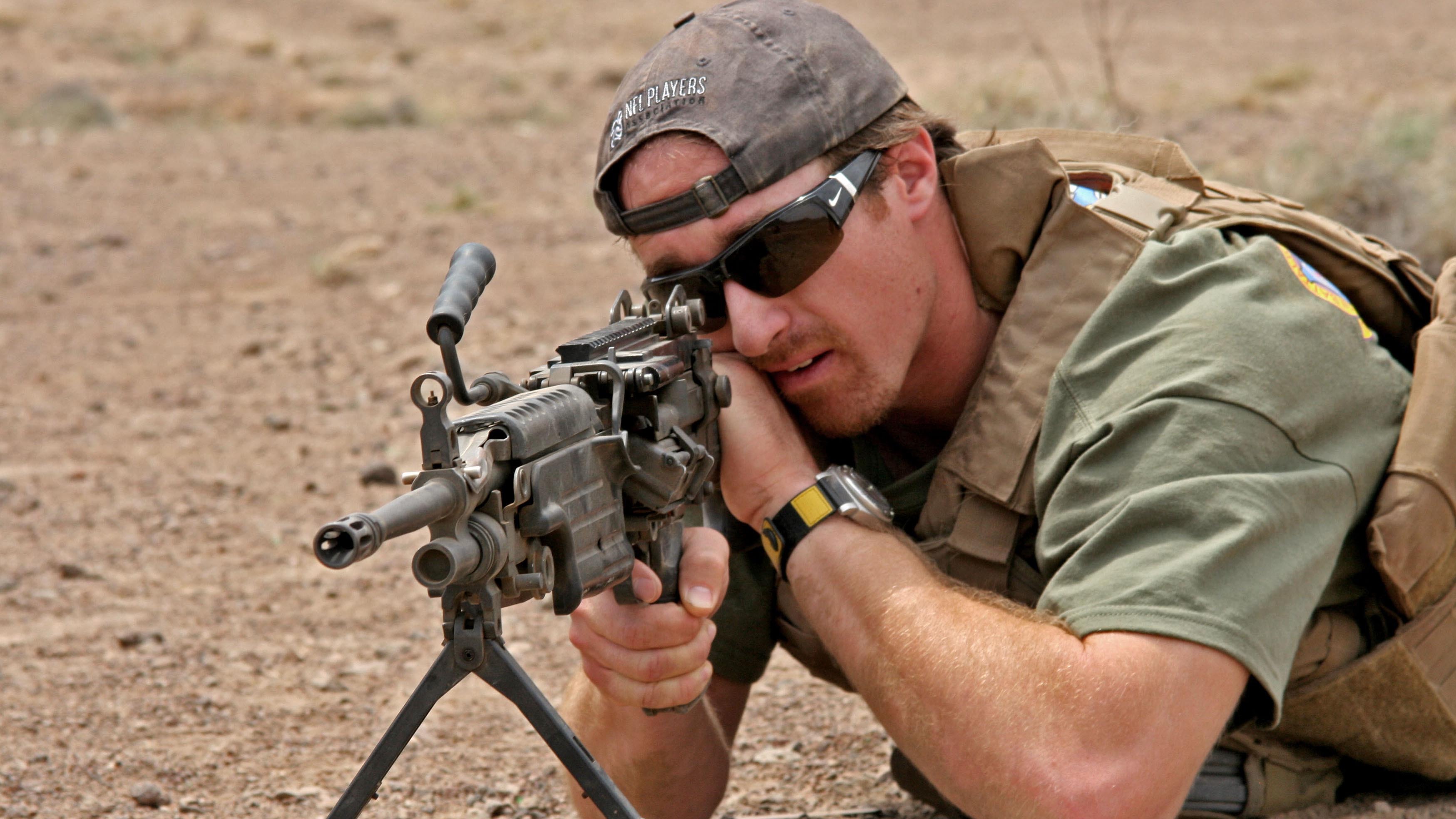 Former New Orleans Saints quarterback Drew Brees looks through the sights of an M249 Squad Automatic Weapon during a USO visit to Marines assigned to the 24th Marine Expeditionary Unit.