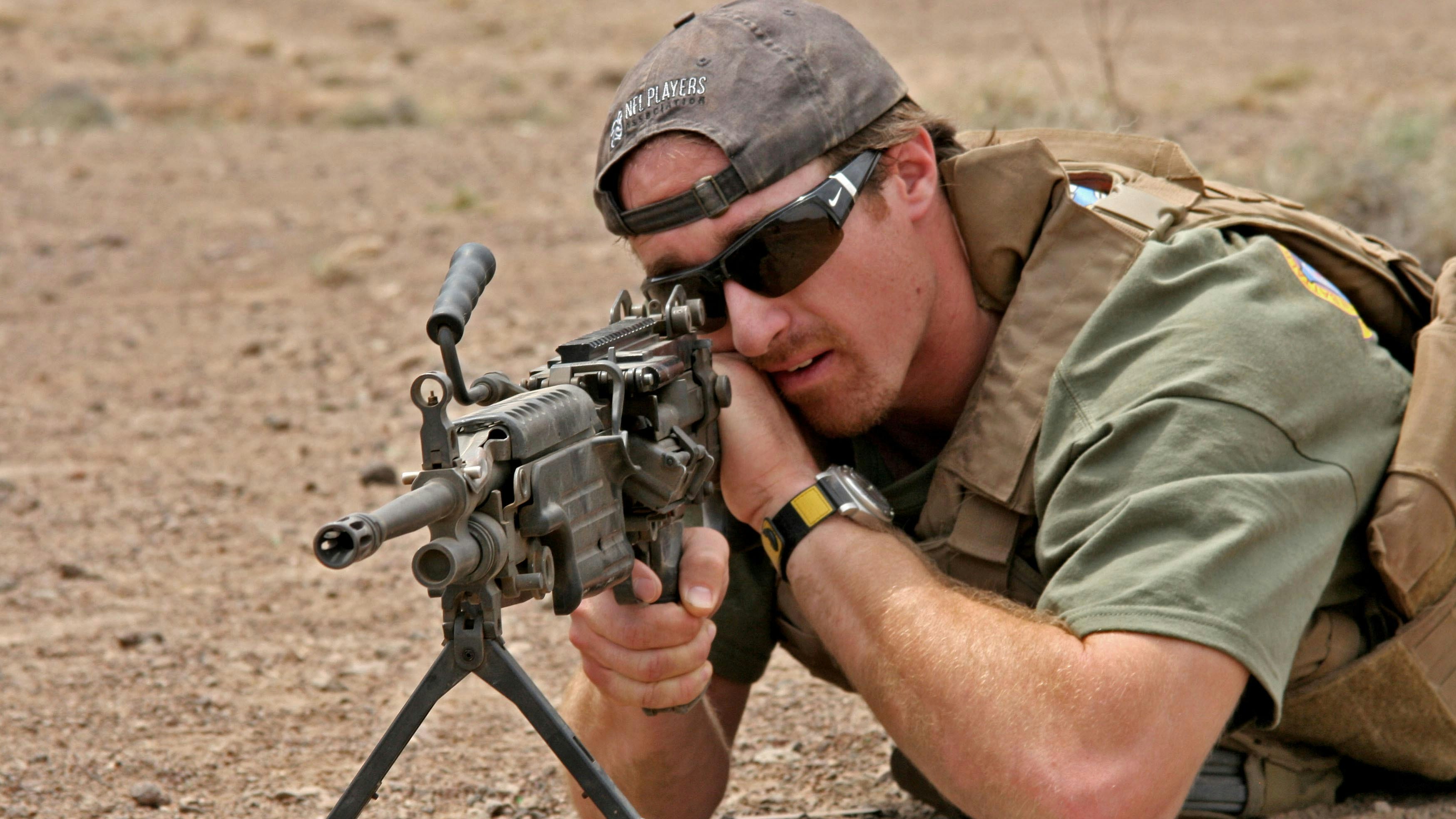 Former New Orleans Saints quarterback Drew Brees looks through the sights of an M249 Squad Automatic Weapon during a USO visit to Marines assigned to the 24th Marine Expeditionary Unit.