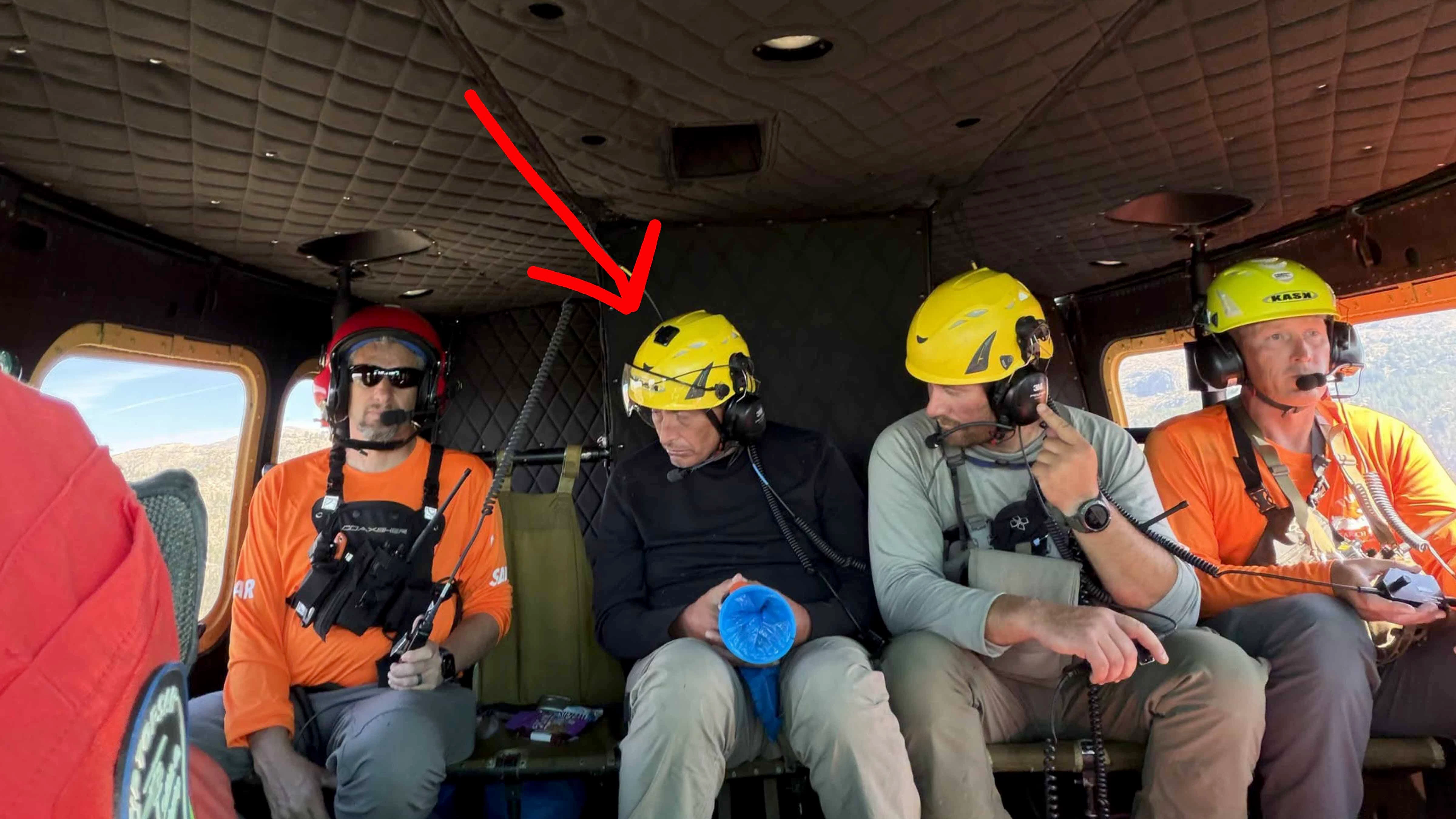 Shaun Mackelprang (second from left) sits aboard a helicopter with search-and-rescue personnel after he was found near Scott Lake on Wednesday