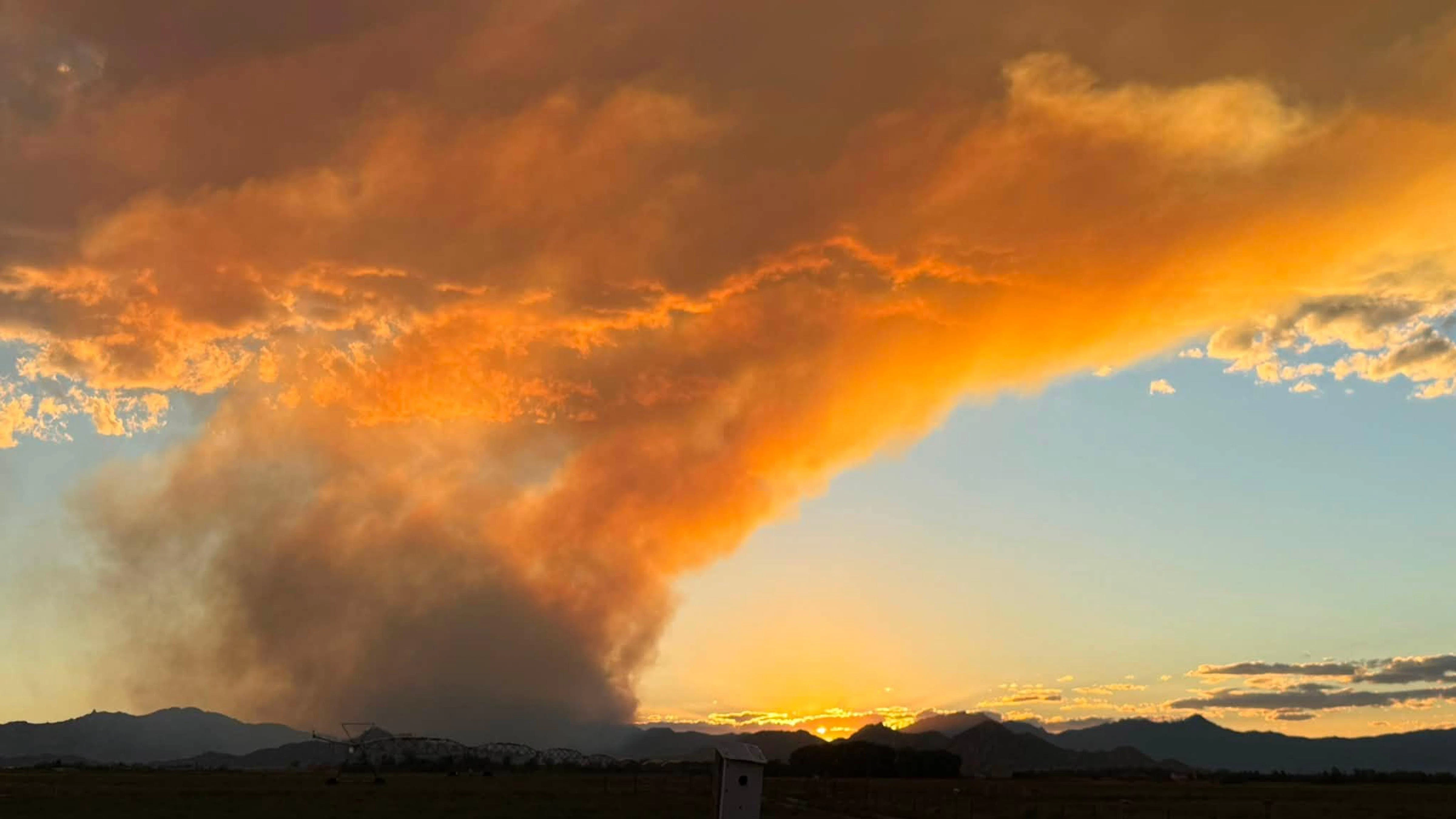 The sun glows red through thick smoke from the Moonshine Fire on Wednesday afternoon as aircraft work above the blaze in the Laramie Range.