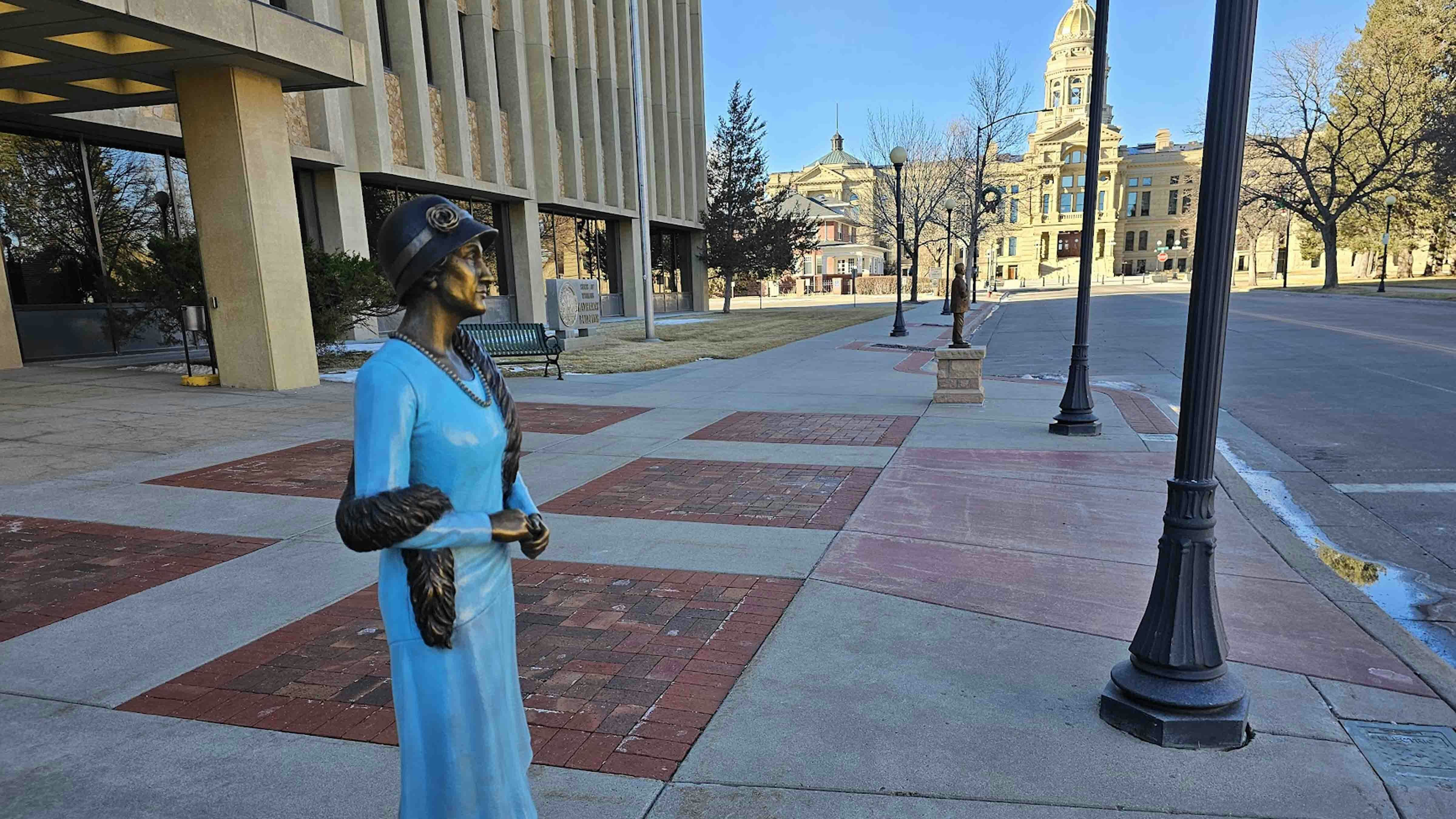 Wyoming's Nellie Tayloe Ross, first female governor in the United States, looks sharp, as if about to turn and walk to Wyoming's state Capitol, in the background