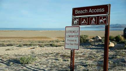 A sign warns visitors of low water levels at the Great Salt Lake's Antelope Island Marina on April 08, 2026 near Syracuse, Utah.