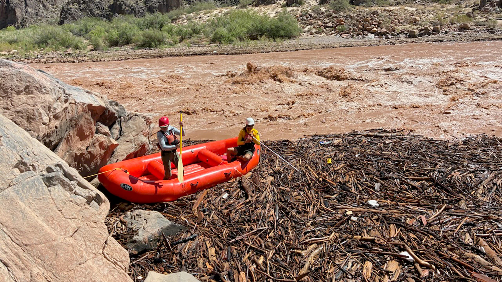 Two rescuers in a raft conduct search operations in a debris pile along the Colorado River near Phantom Ranch.