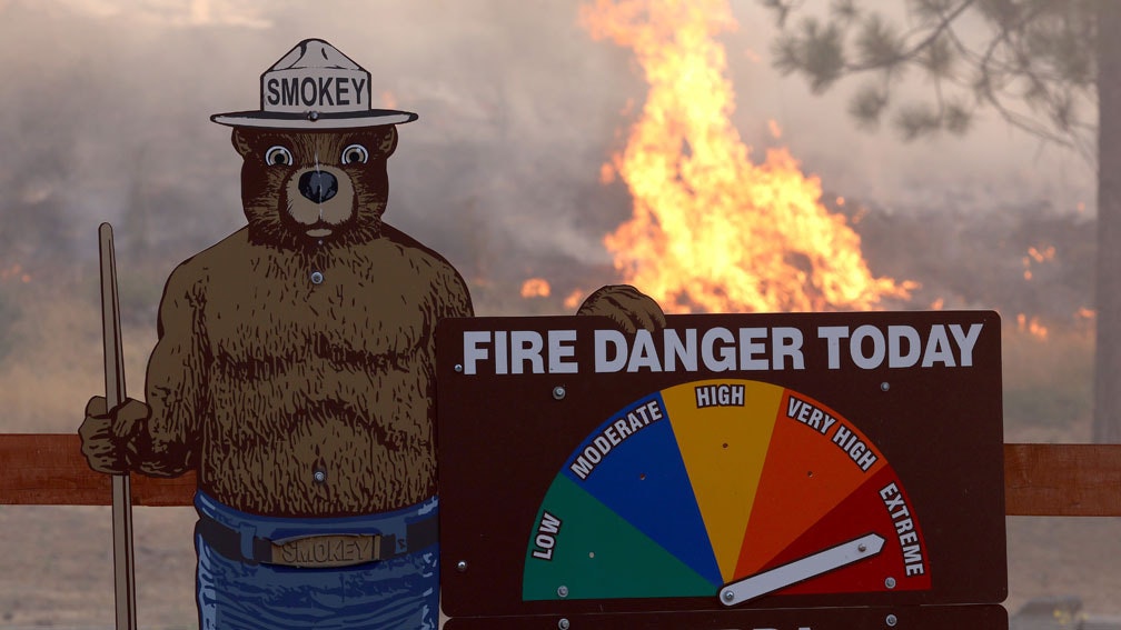 Fire burns near a Smokey the Bear fire warning sign