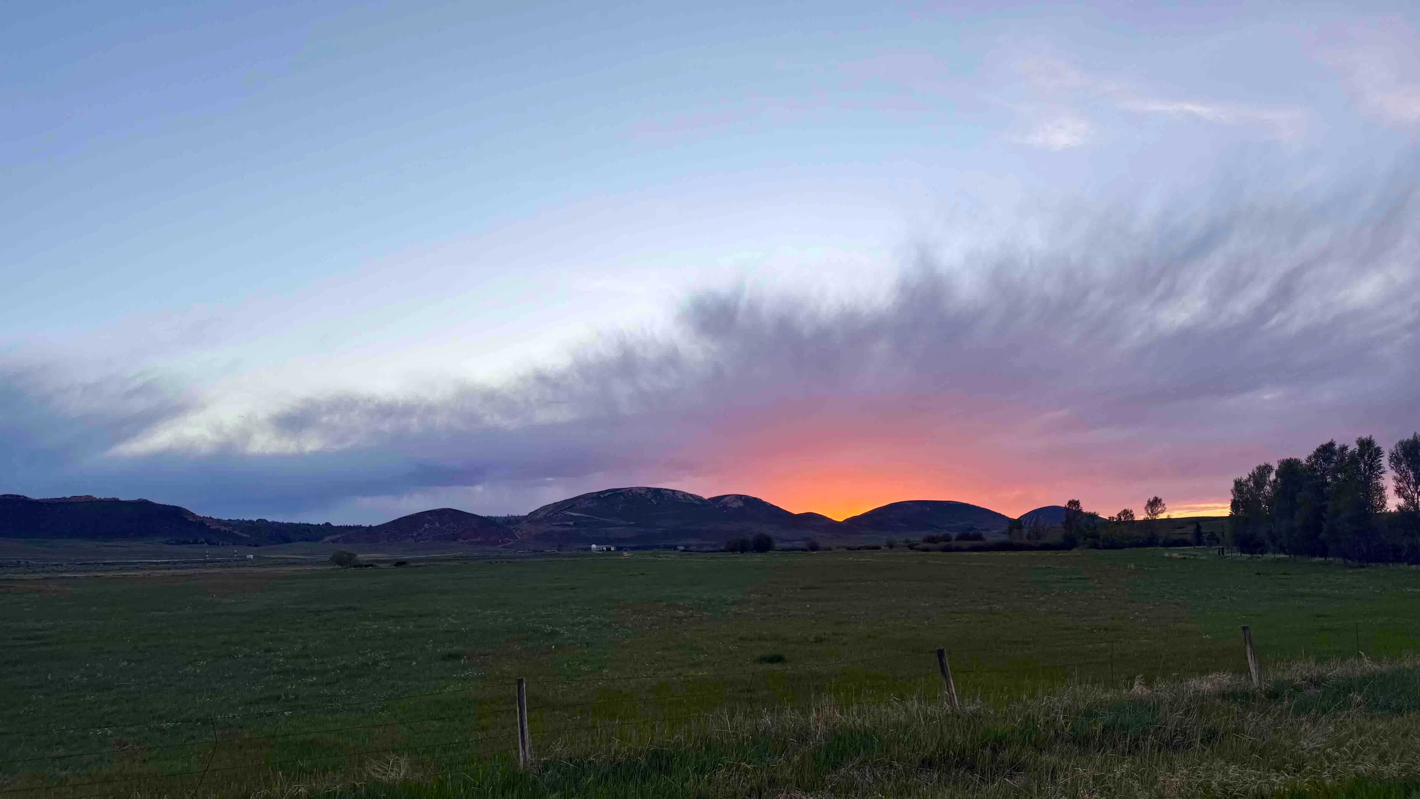 The setting sun slips behind the hills of Horse Creek, Wyoming, casting a brilliant orange glow across the horizon.