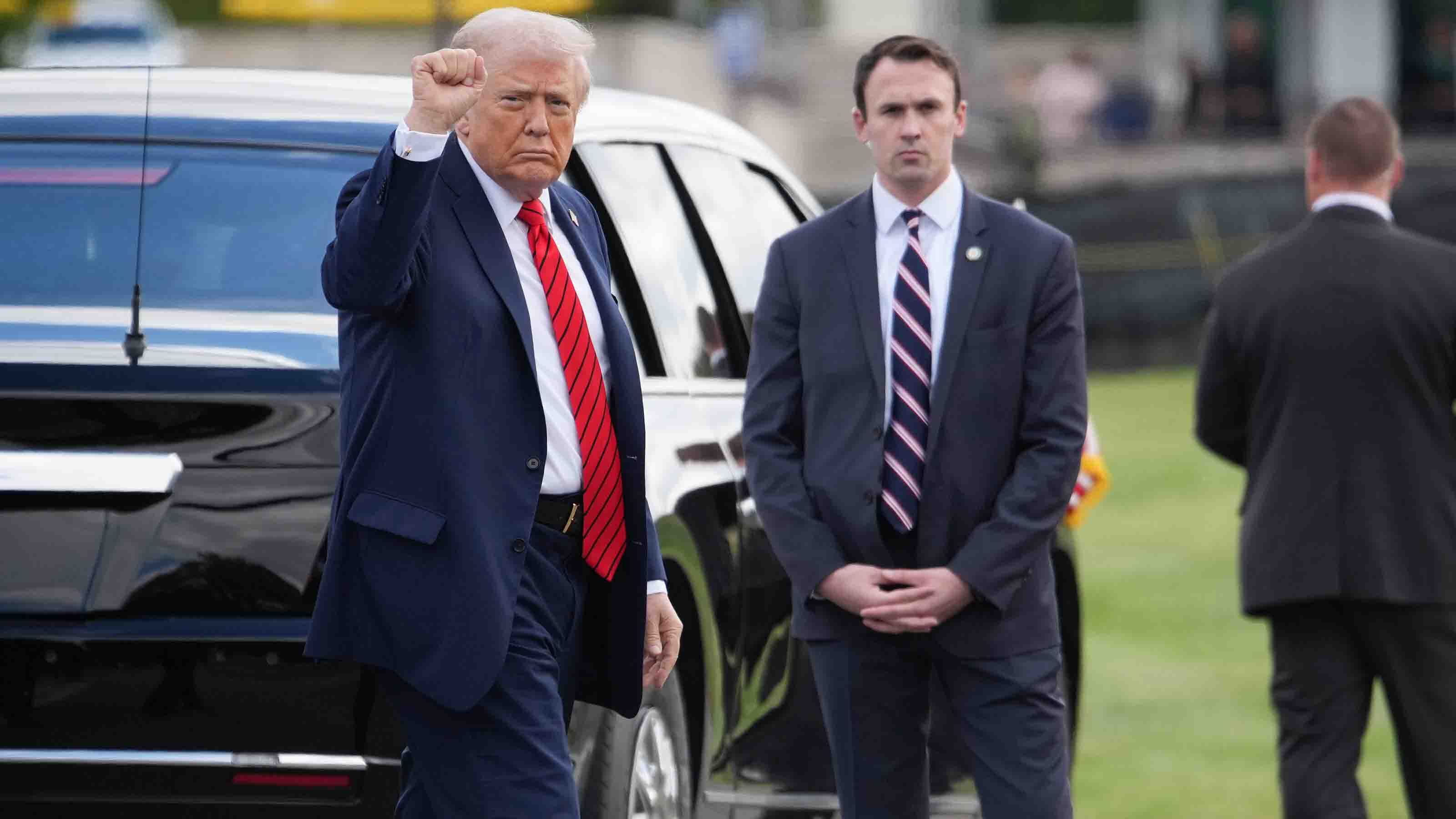 President Donald Trump pumps his fist while gesturing toward members of the media as he departs Walter Reed Medical Center on October 10, 2025 in Bethesda, Maryland. Trump traveled to Walter Reed to visit with troops and receive a medical check up.