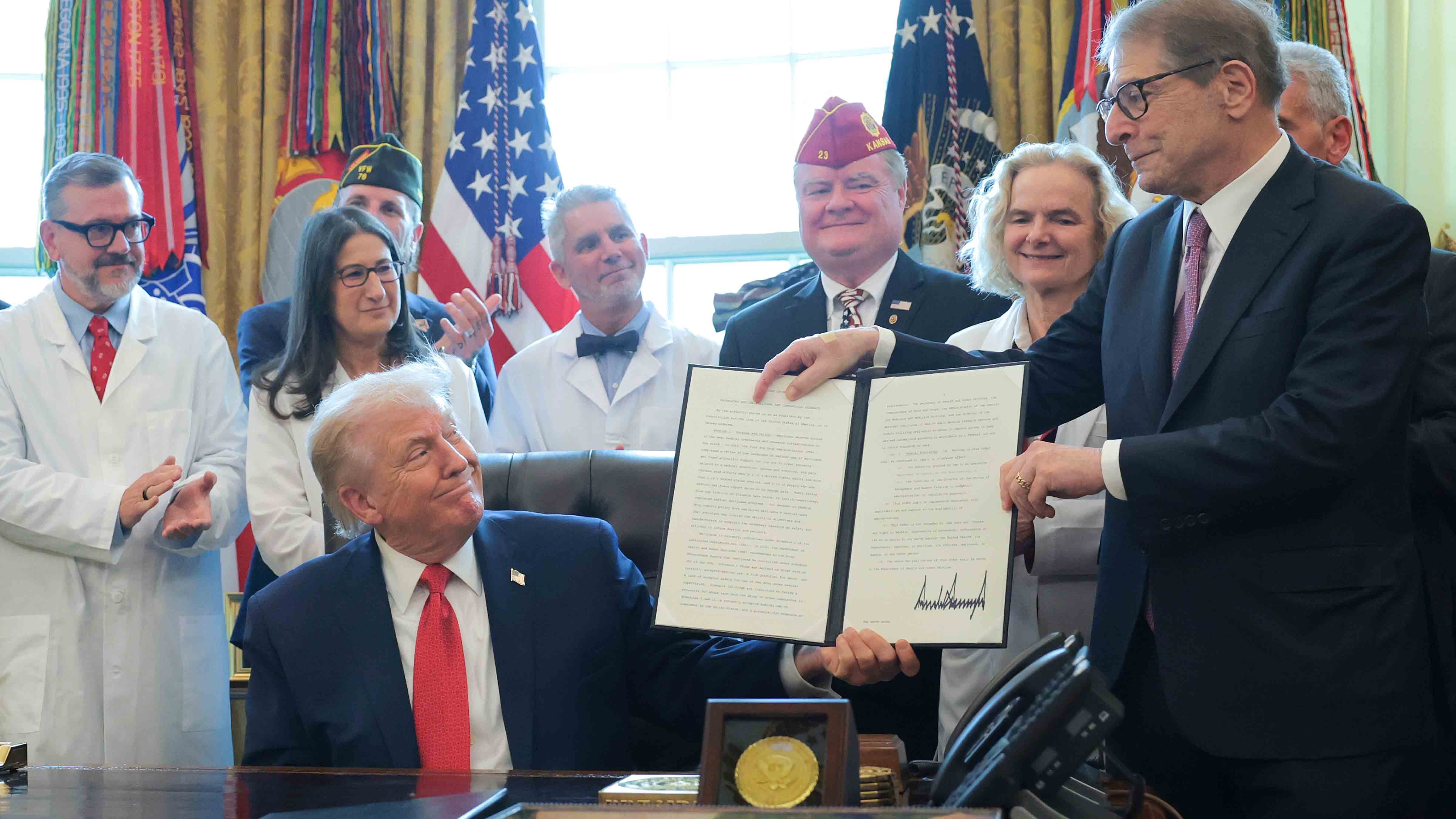 U.S. President Donald Trump displays an executive order with Howard Kessler (R) that Trump signed in the Oval Office of the White House on December 18, 2025 in Washington, DC. During the ceremony, Trump signed the order reclassifying marijuana as a schedule III drug.