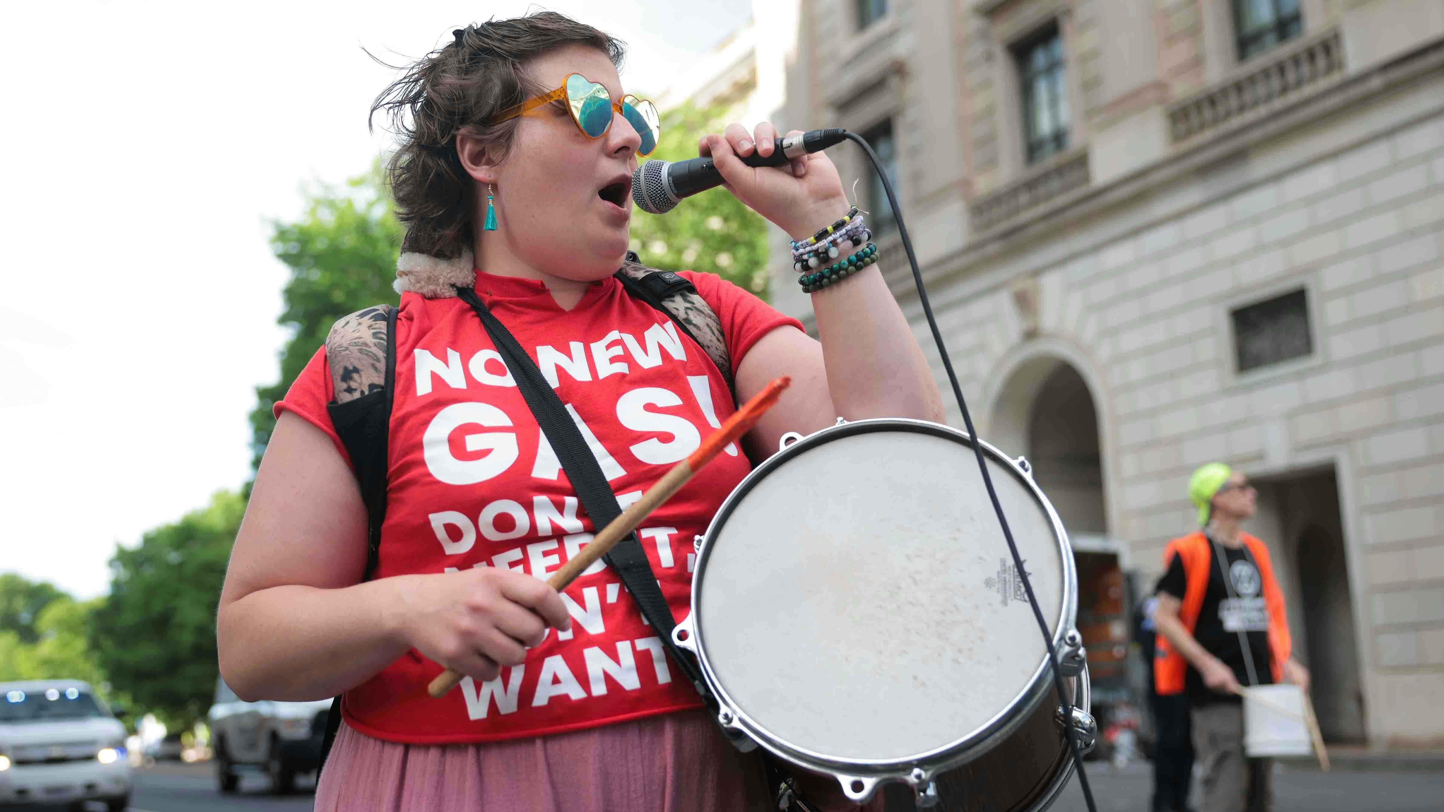 A protester shouts into a microphone and hits a drum while marching through the streets to demonstrate against U.S. President Donald Trump's first 100 days in office on April 30, 2025 in Washington, DC.
