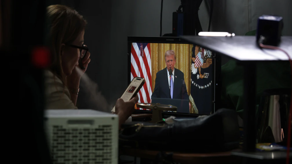 TV reporter watches U.S. President Donald Trump address the nation on the grounds of the White House on July 16, 2026 in Washington, DC. Trump is expected to speak on election security.