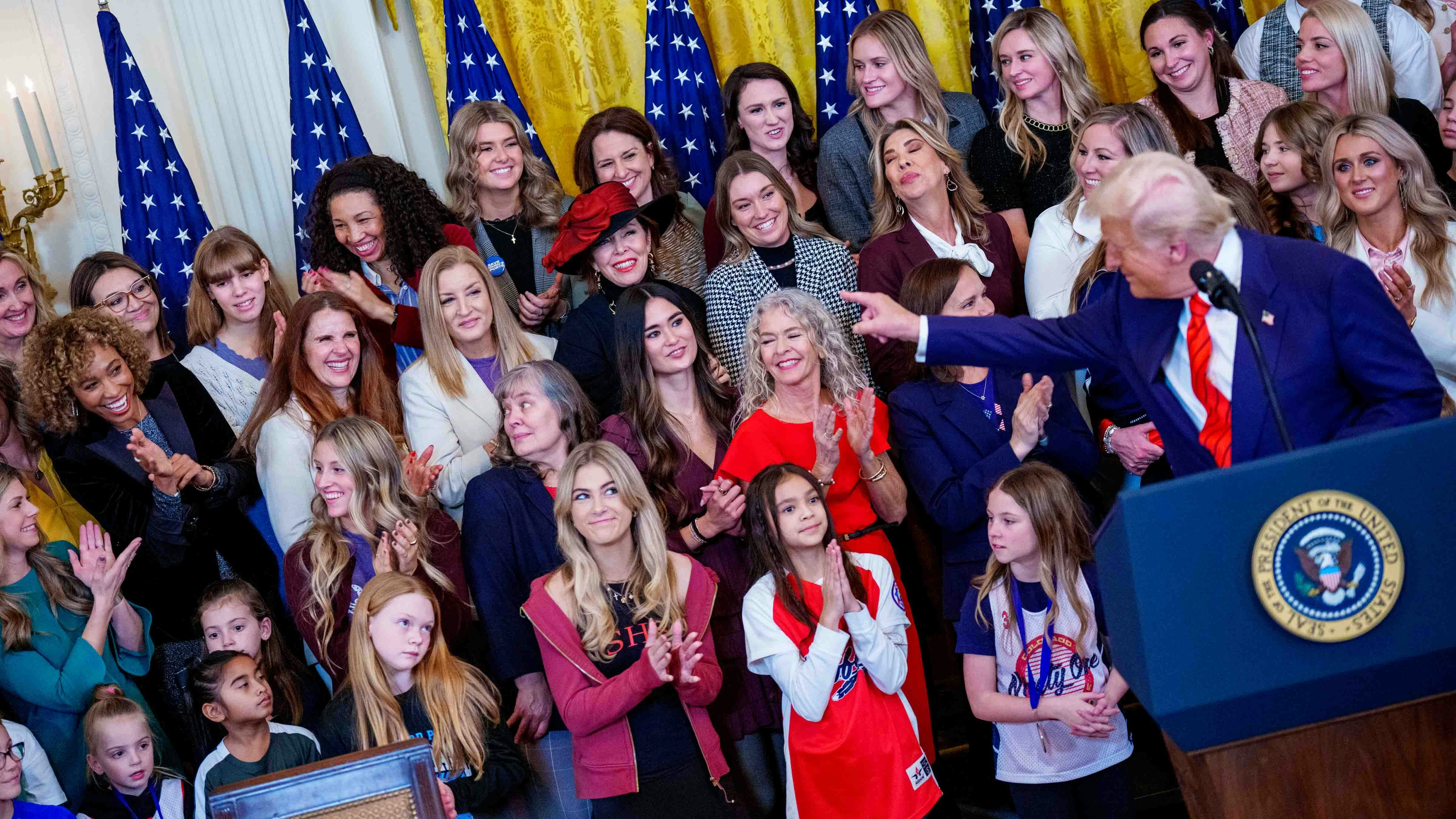 Sage Steele (L) reacts while standing behind U.S. President Donald Trump as he recognizes her before he signs the "No Men in Women's Sports" executive order in the East Room of the White House on February 5, 2025 in Washington, DC.