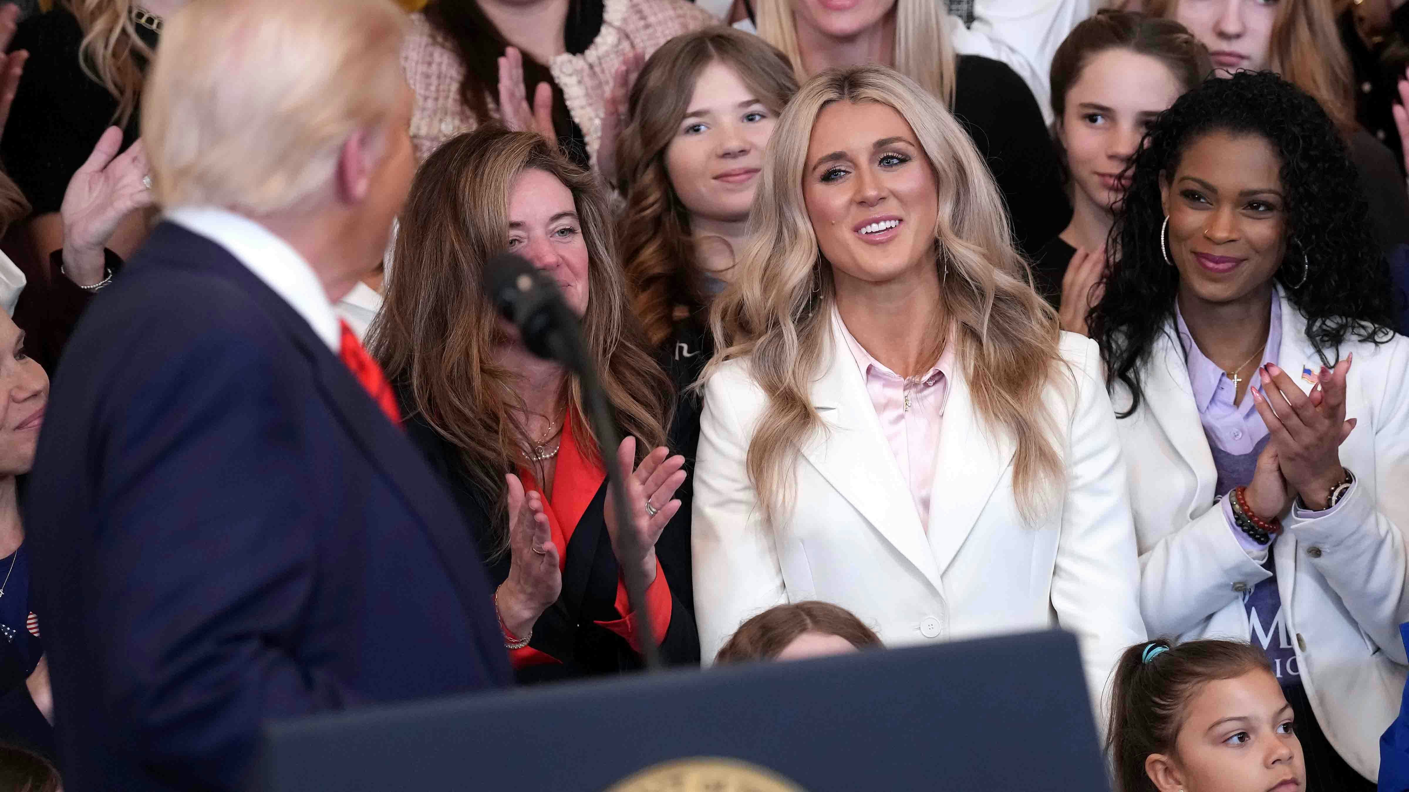 Political activist and former competitive swimmer Riley Gaines (C) watches as U.S. President Donald Trump delivers remarks before signing the “No Men in Women’s Sports” executive order in the East Room at the White House on February 5, 2025 in Washington, DC.