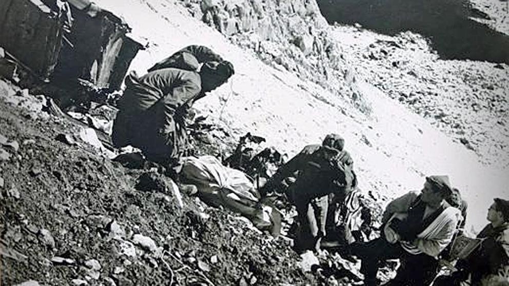 Volunteers are shown placing remains in body bags at the site where United Airlines Flight 409 crashed into Medicine Bow Peak in the early morning of Oct. 6, 1955. Reporter Dick Perue is shown on the far right of this photo.