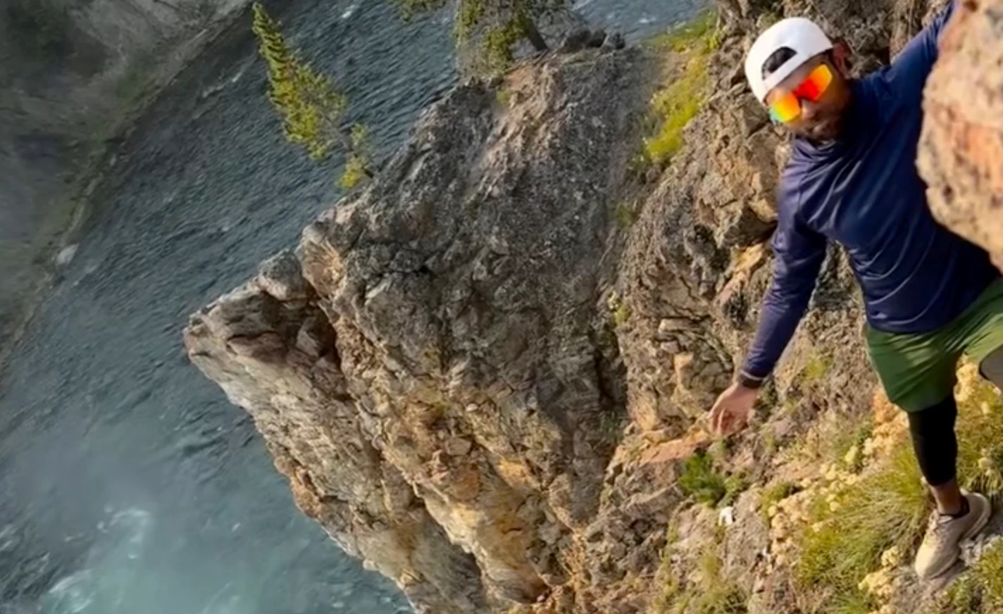 A dimwitted tourist shared a video of himself illegally perched above the 109-foot-tall summit of the Upper Falls of the Grand Canyon in Yellowstone.